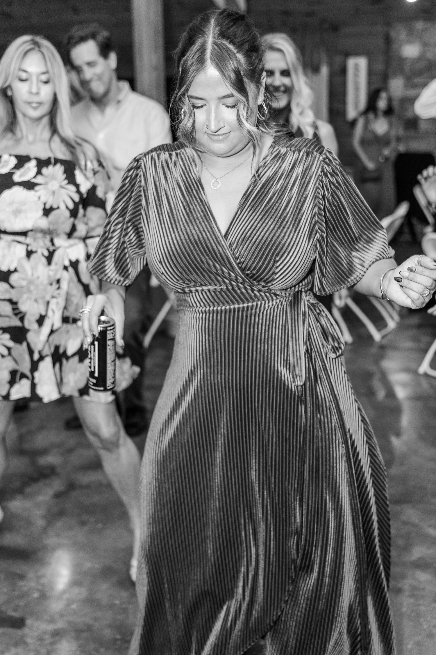 Wedding guests dance and celebrate on the reception dance floor in a rustic venue.