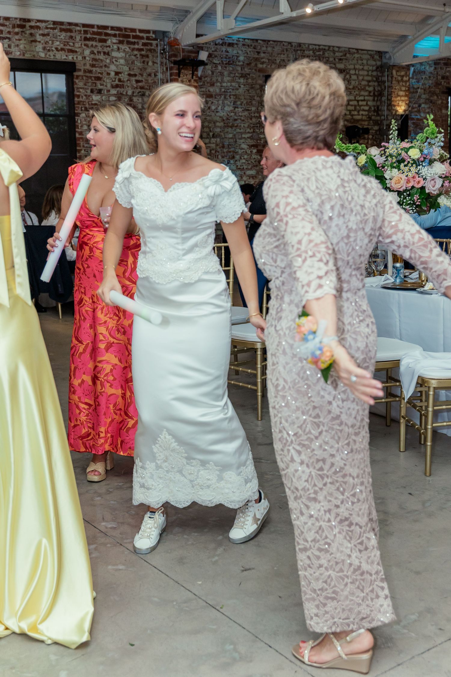 Wedding party dancing and celebrating on the dance floor with guests wearing yellow and red formal attire.
