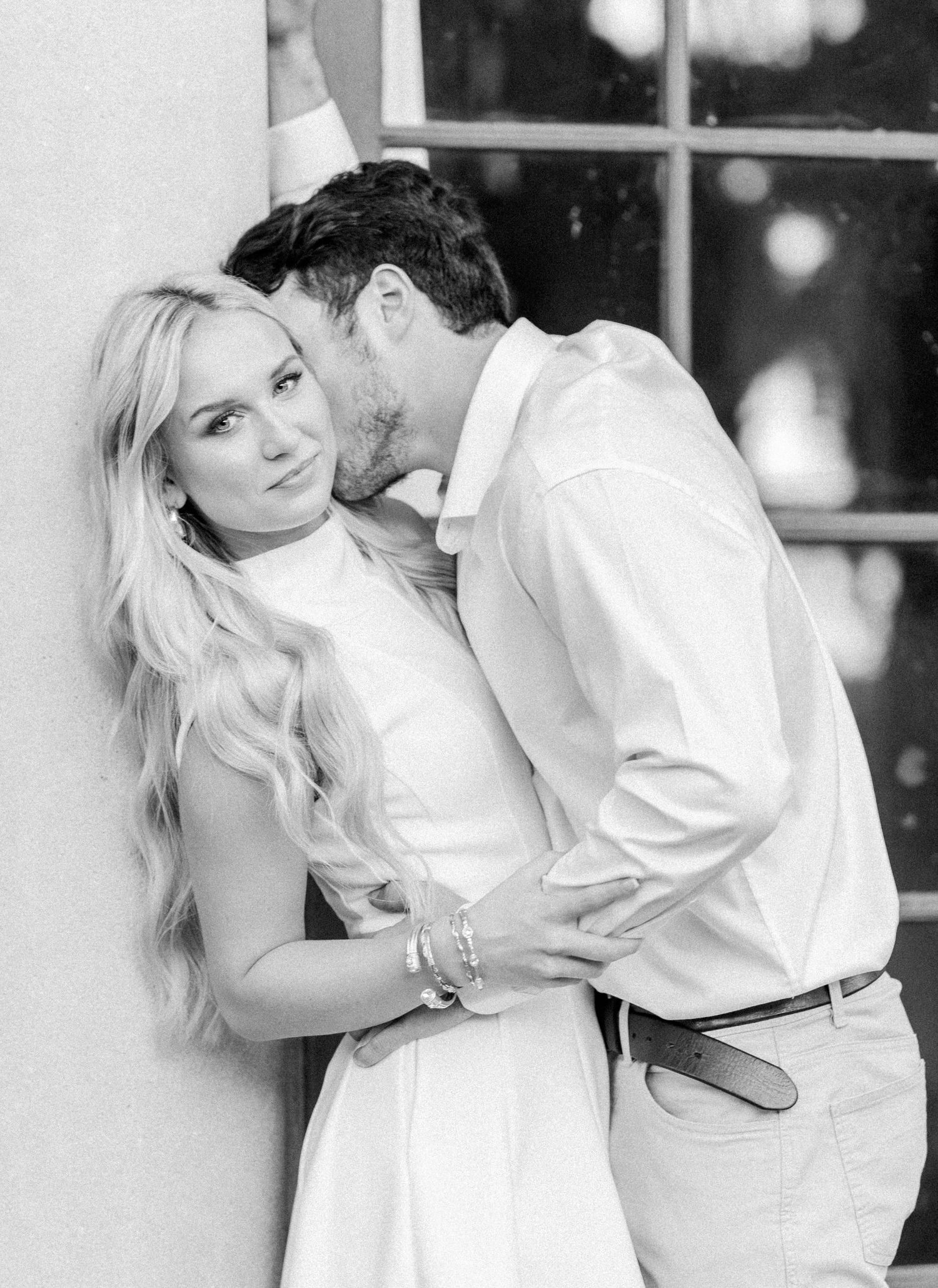 Black and white romantic photos showing a couple in white attire posing together at a vintage venue.