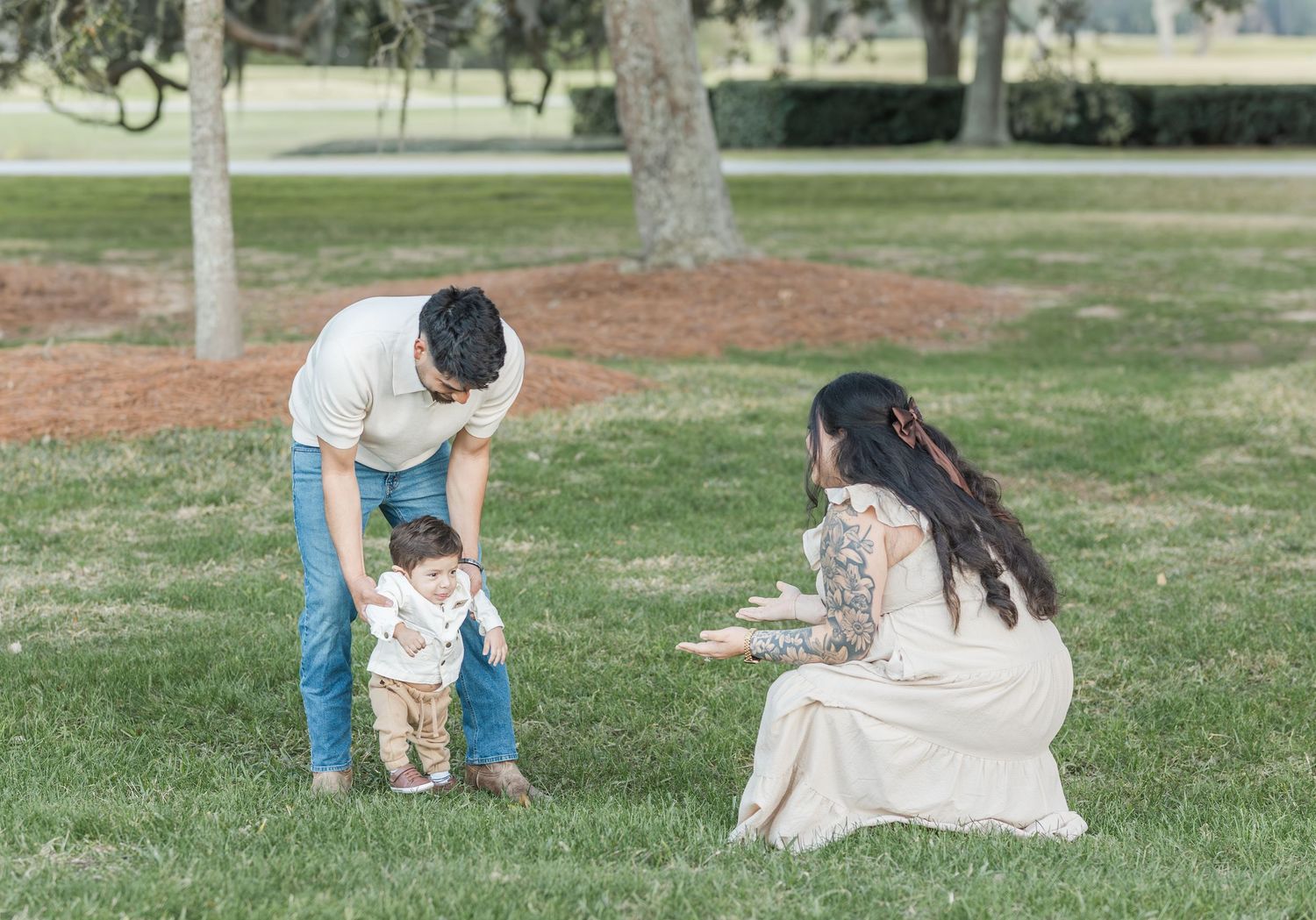 Family enjoying playful moments together on a grassy lawn in a park setting.