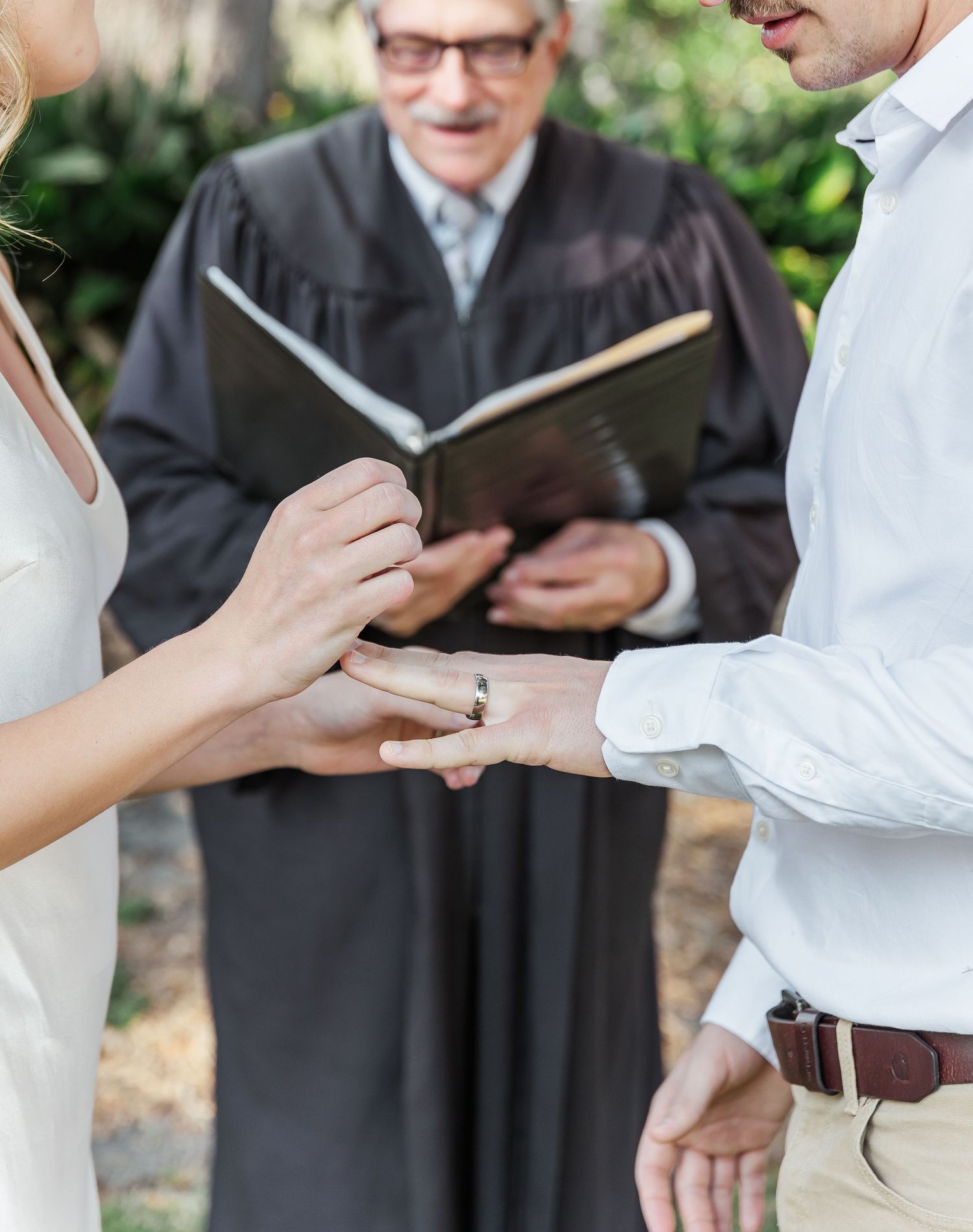 Close up of ring exchange during outdoor wedding ceremony with officiant.