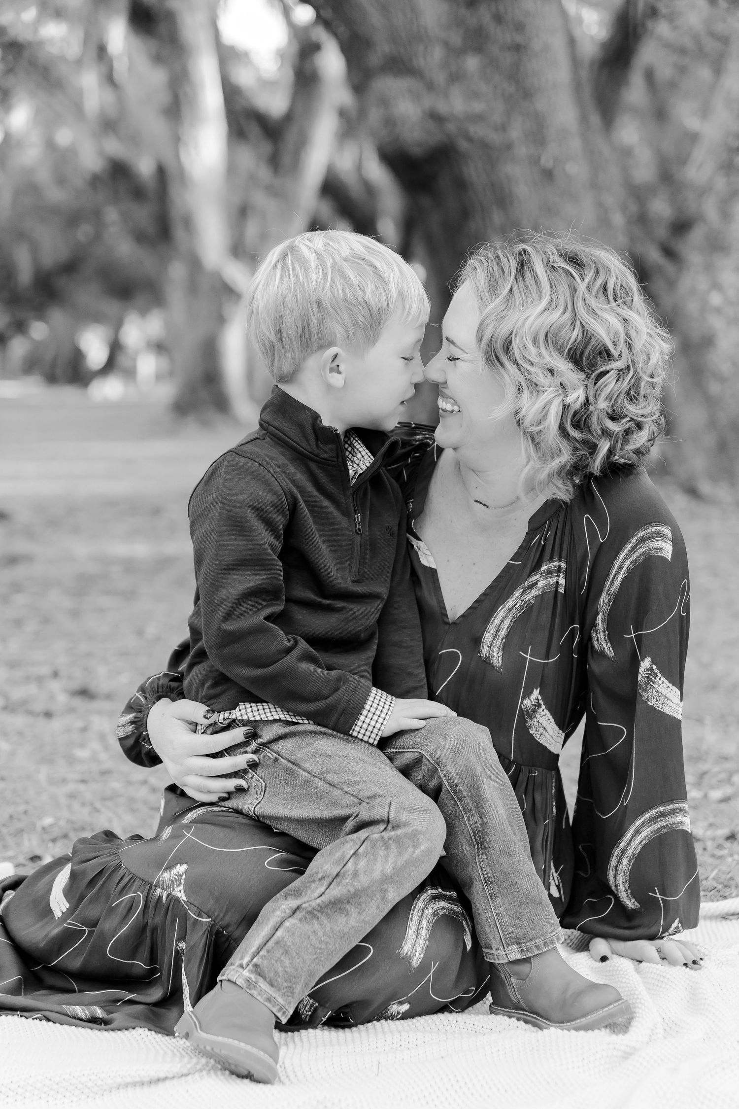 Black and white photo of a tender moment between parent and child on a blanket outdoors.