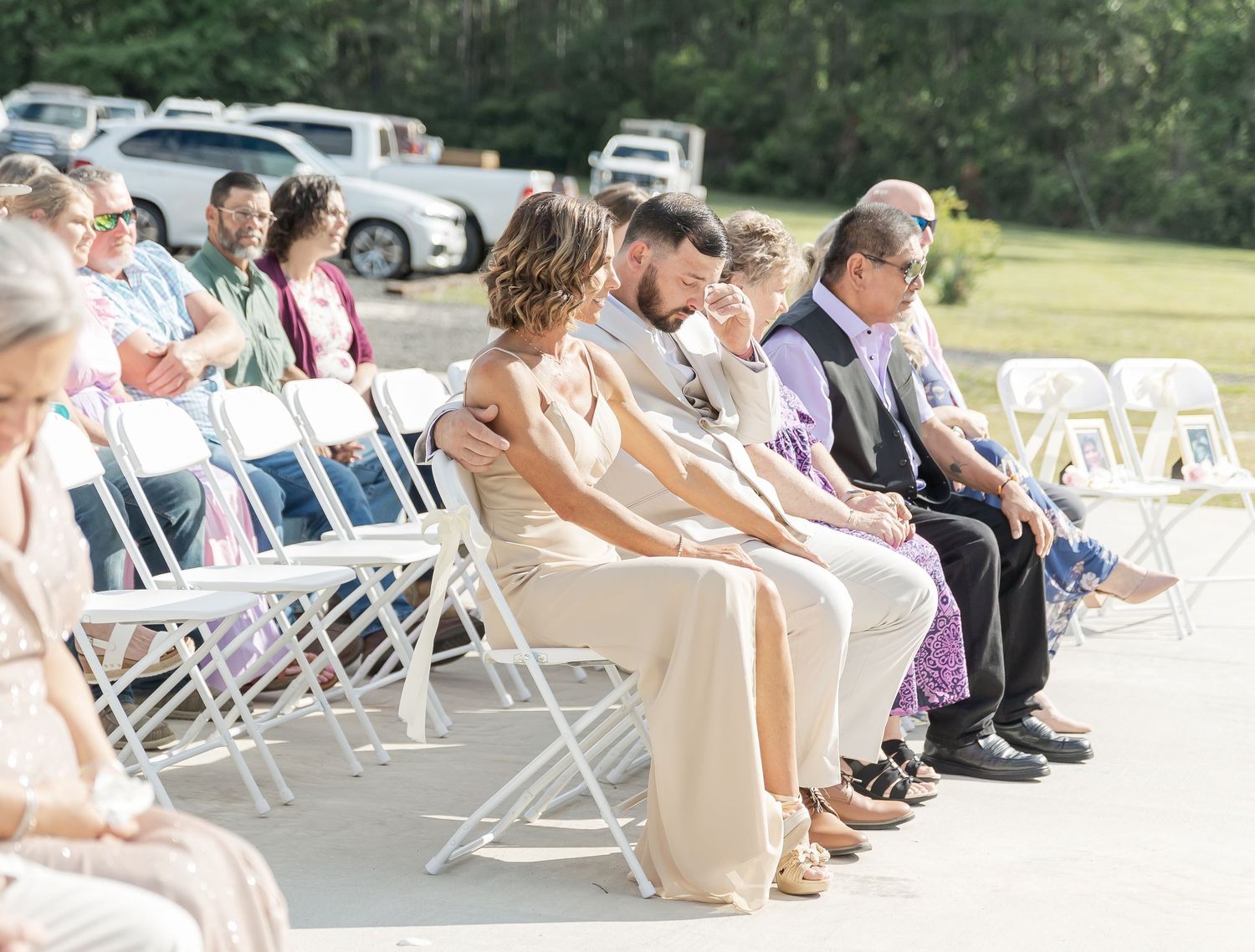 Wedding guests seated in white folding chairs during an outdoor ceremony.