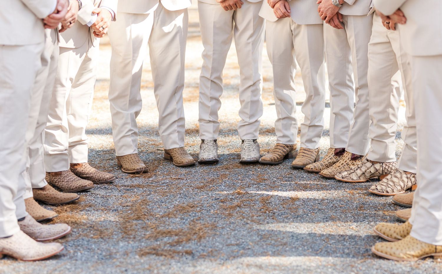 Close-up of groomsmen standing in a circle showing off matching woven loafer wedding shoes.