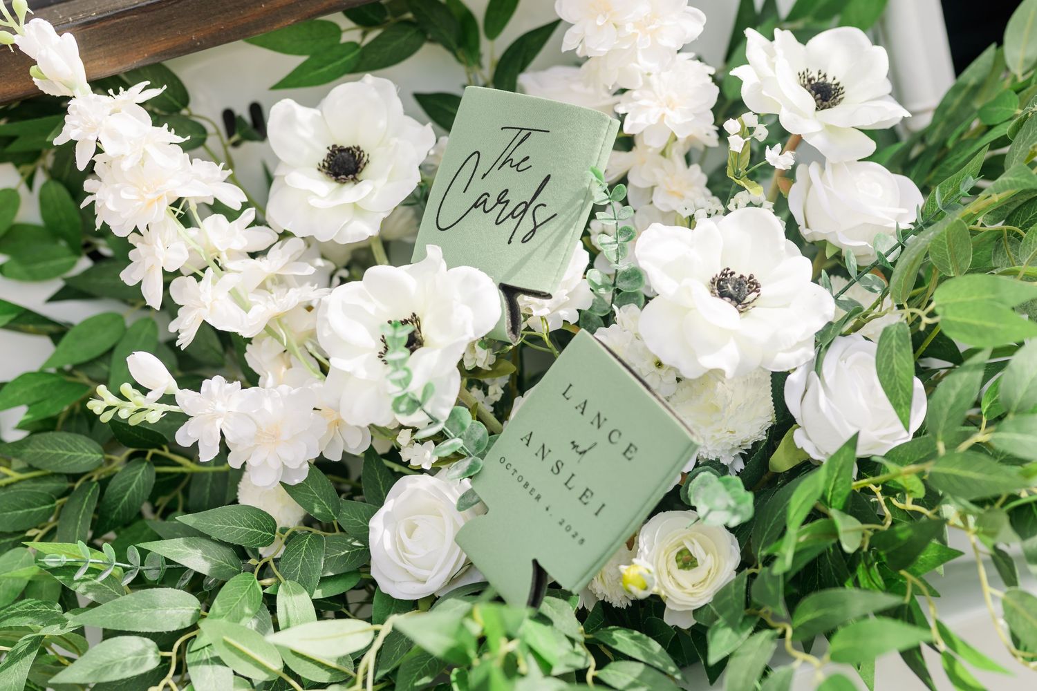 White floral arrangements with green foliage and handwritten cards create an elegant wedding display.
