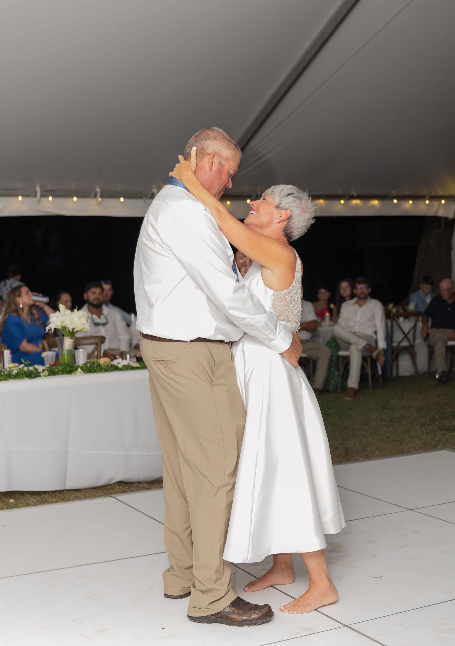 Couple embraces during a romantic slow dance at their outdoor wedding reception.
