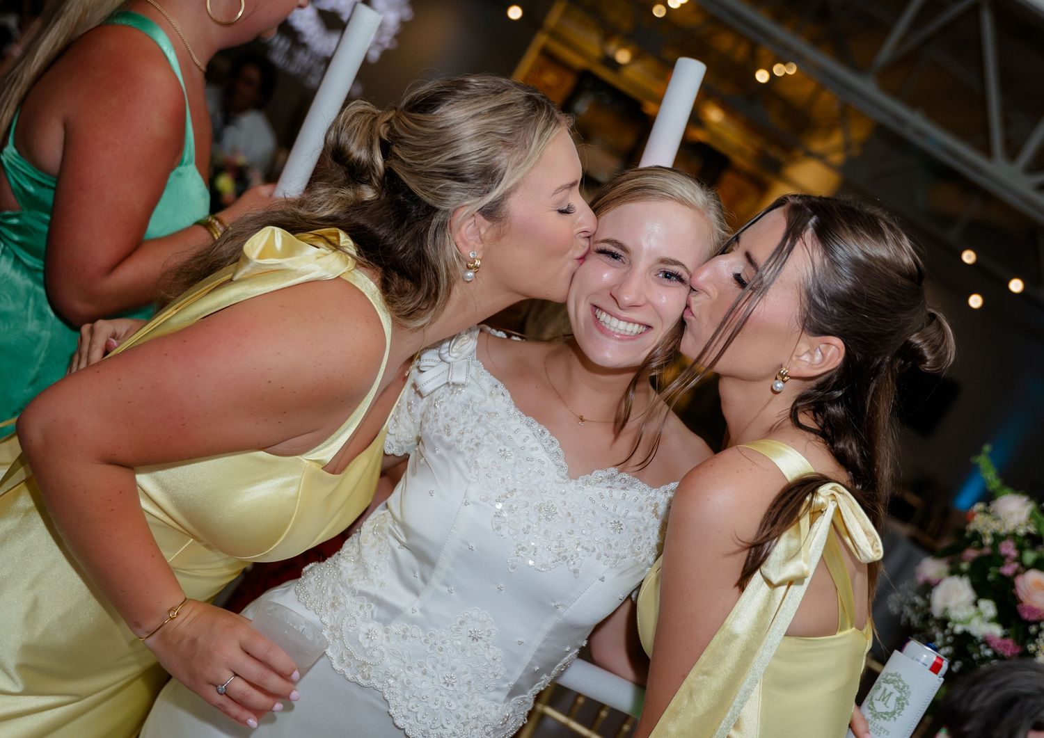 Wedding party members celebrating with glow sticks in yellow bridesmaid dresses.