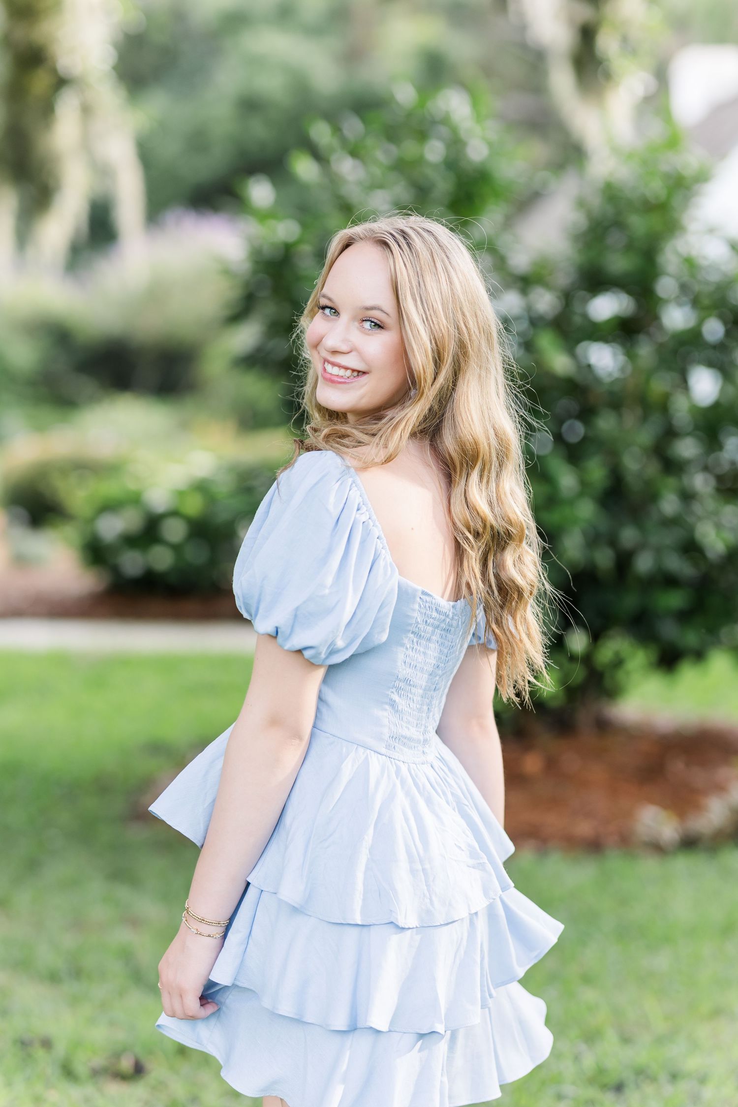 A light blue ruffled dress with puff sleeves photographed in a garden setting.
