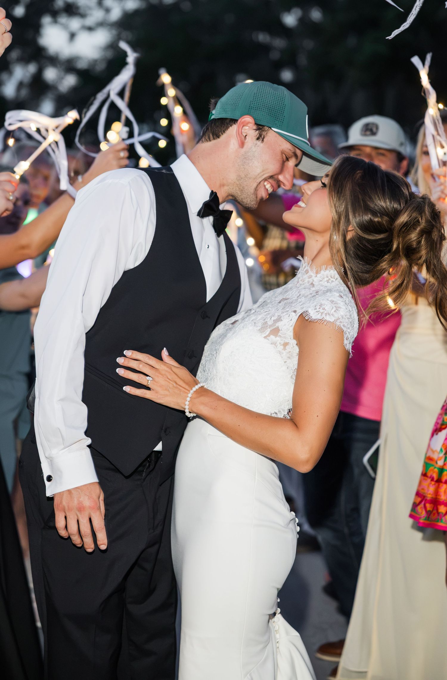 Bride and groom share a romantic moment surrounded by guests with light wands at their outdoor wedding reception.