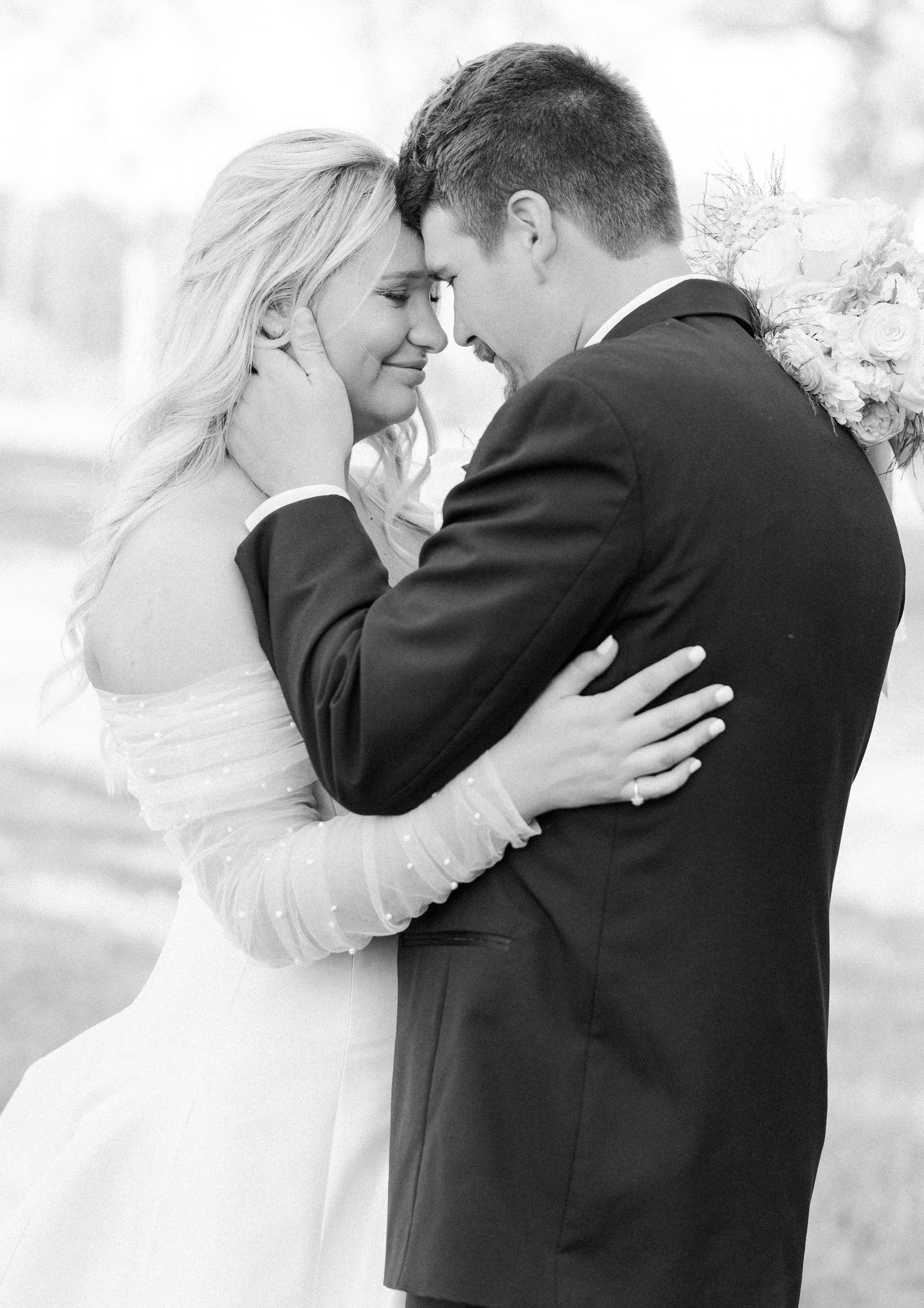 Bride and groom sharing an intimate forehead touch in black and white wedding photo.