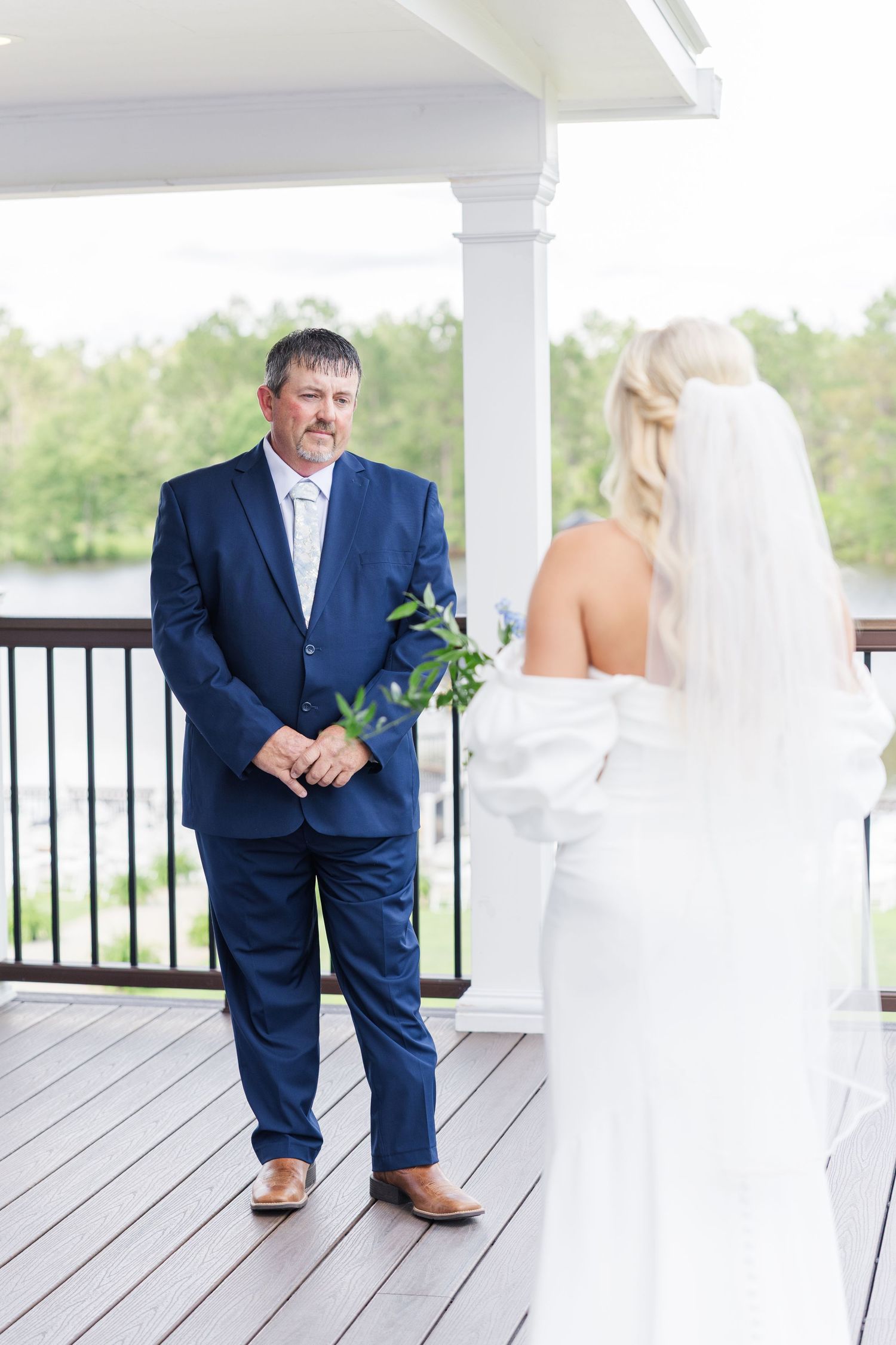 Emotional father sees bride in white off-shoulder gown for the first time during outdoor first look.