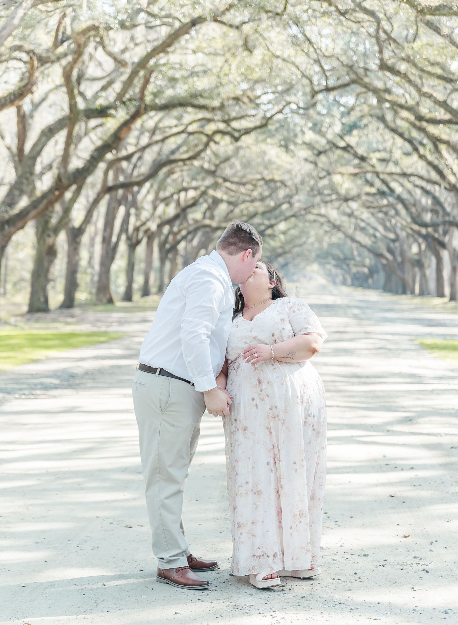 A tender romantic moment shared between a couple under an oak tree canopy.