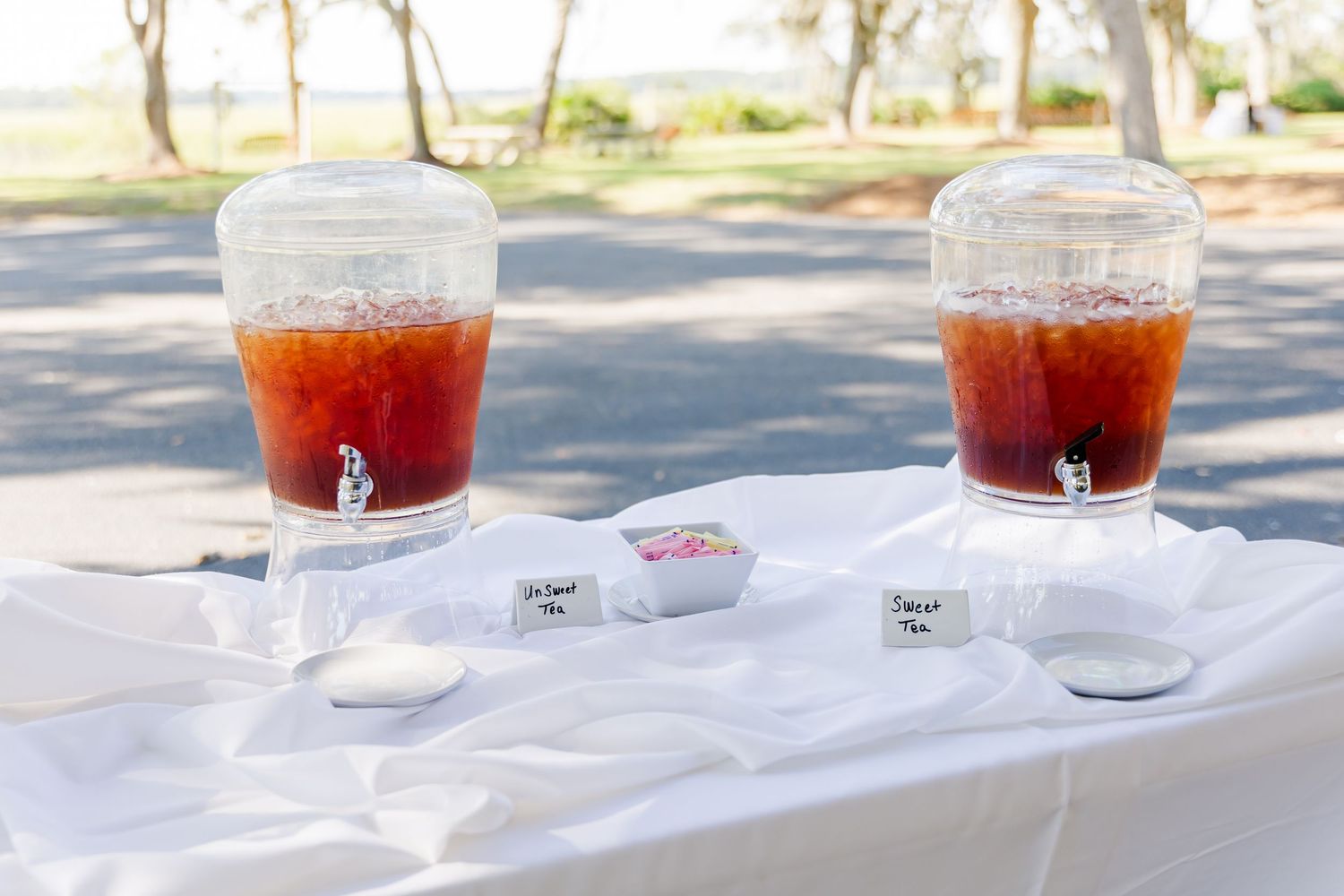 Red cocktails in clear glasses displayed on a white tablecloth at an outdoor event.