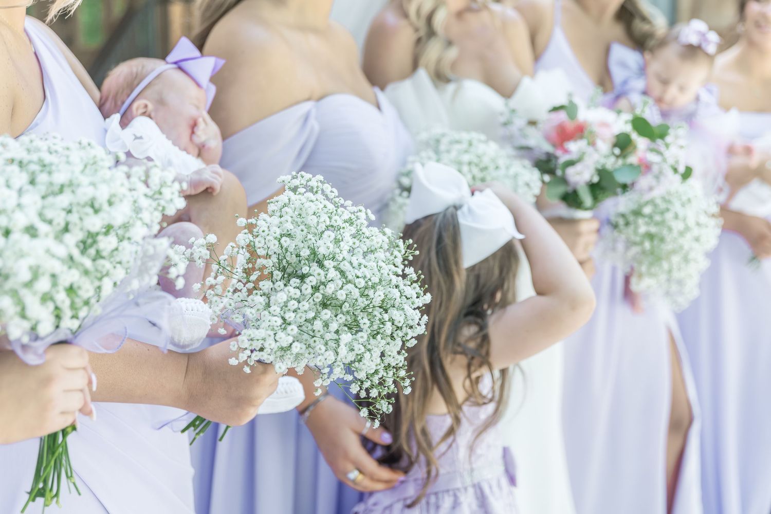 Close-up of bridesmaids holding delicate baby's breath bouquets in soft natural lighting.