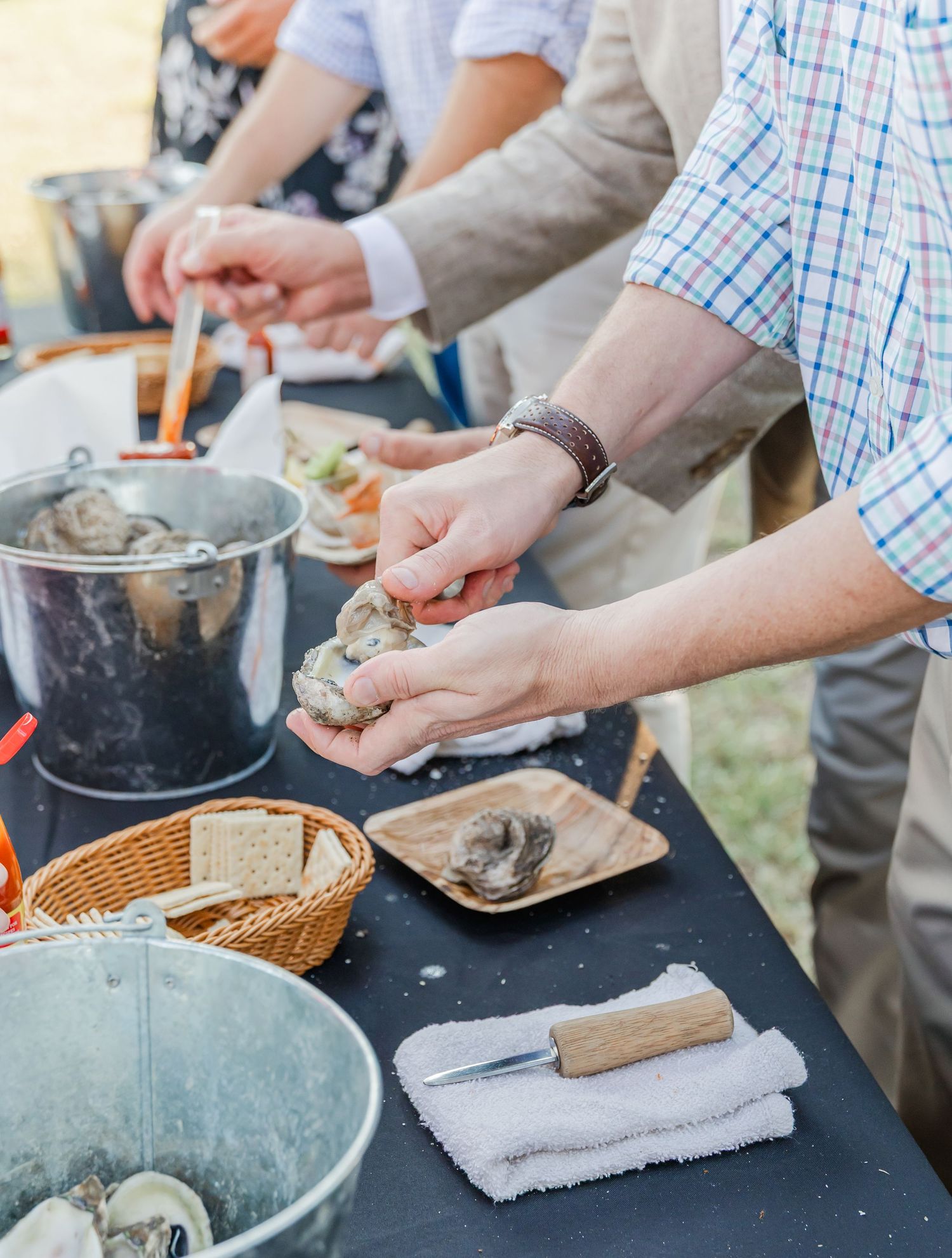 People kneading and shaping dough on a black table surface during a cooking activity.