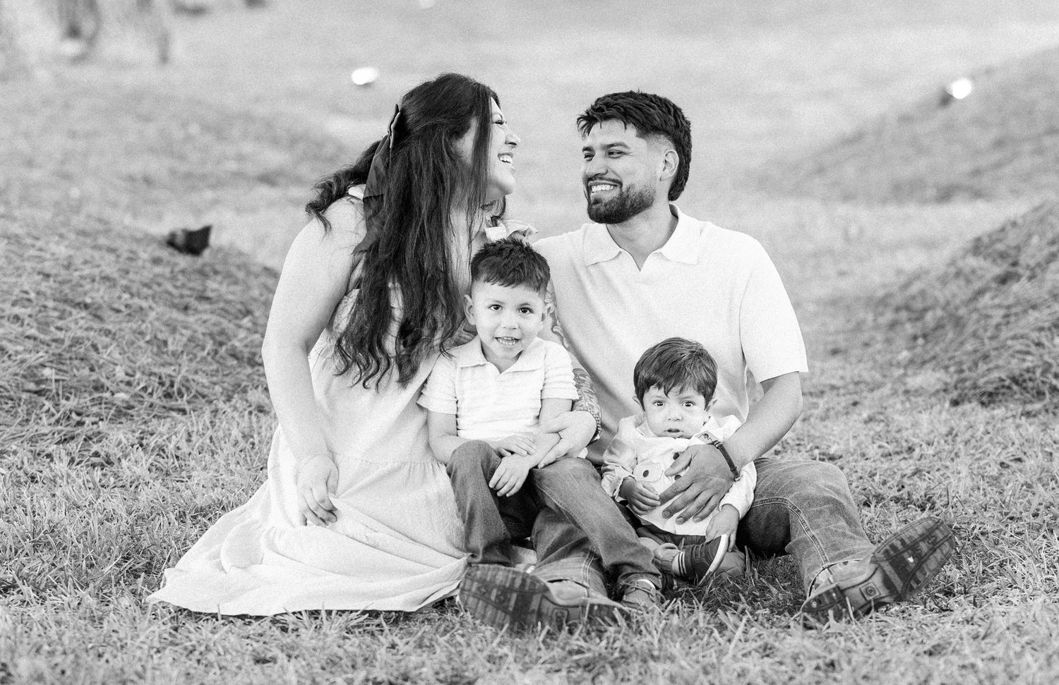 Black and white family portrait session captured on a grassy hillside.