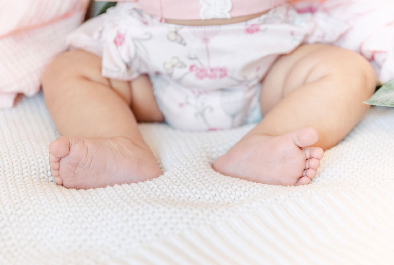Close-up of tiny bare feet on white textured fabric.