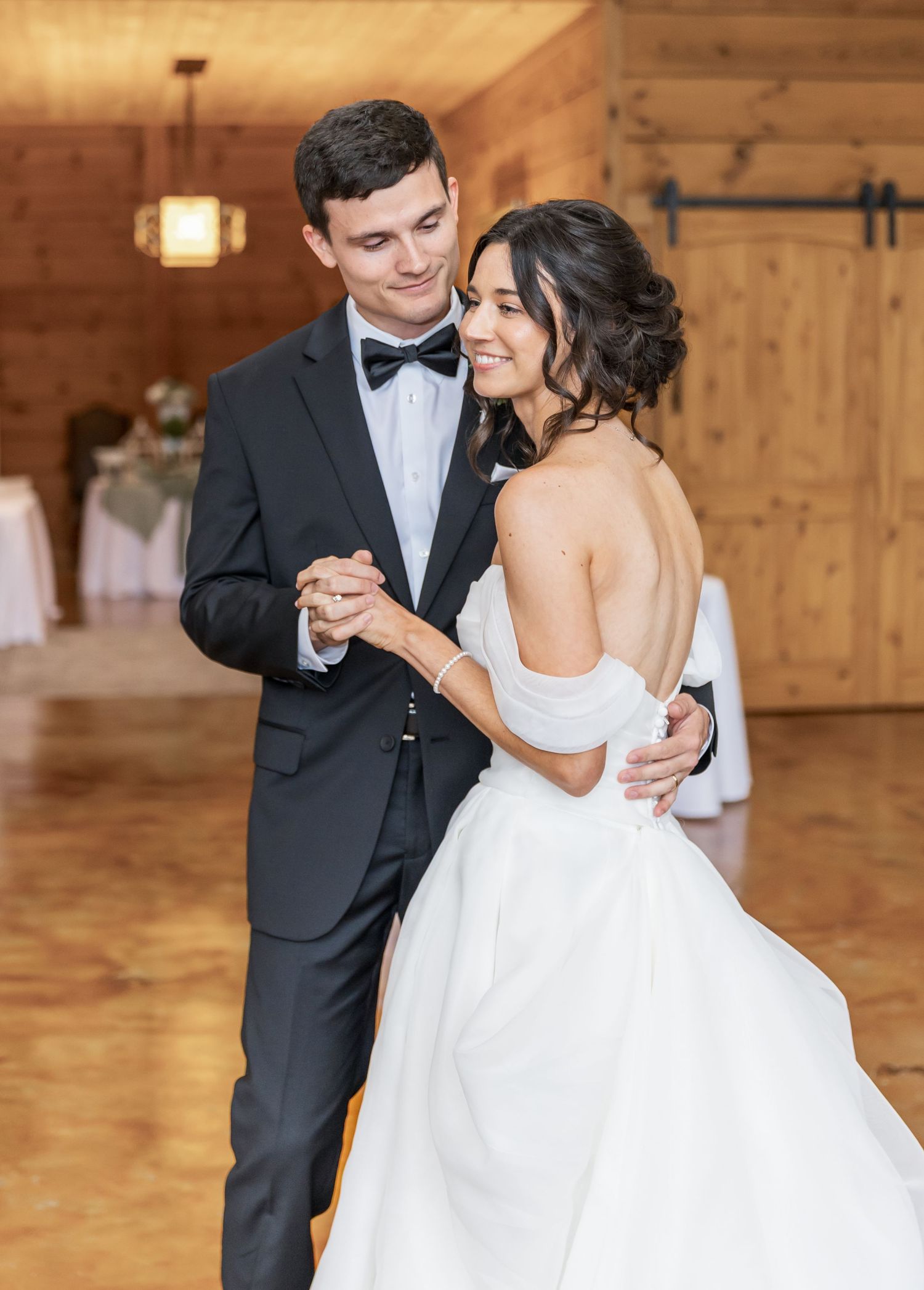 A couple dances together in an intimate moment on their wedding day in a rustic wooden venue.