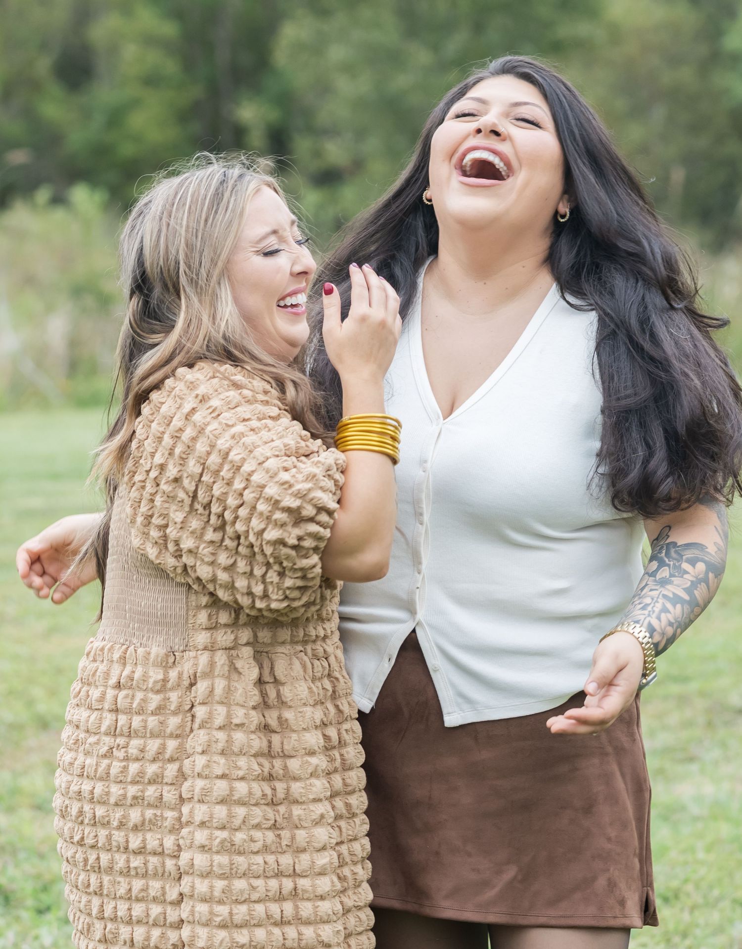 Two friends sharing genuine laughter while wearing casual outfits in an outdoor setting.