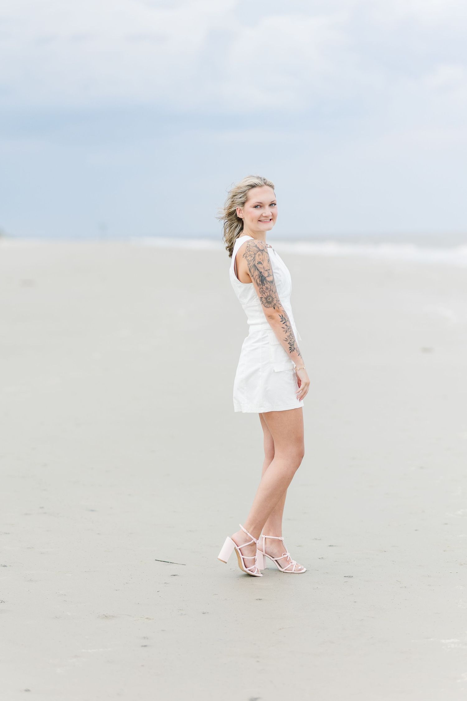 Ethereal beach scene showing a white-clad figure walking along pristine sand under bright skies.