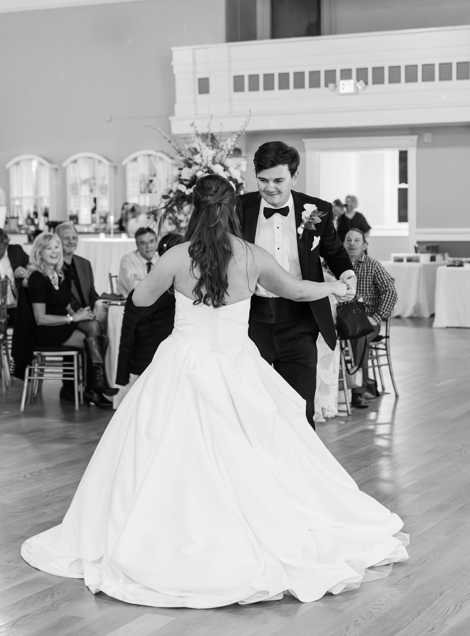 Bride and groom share their first dance at elegant wedding reception in black and white photo.