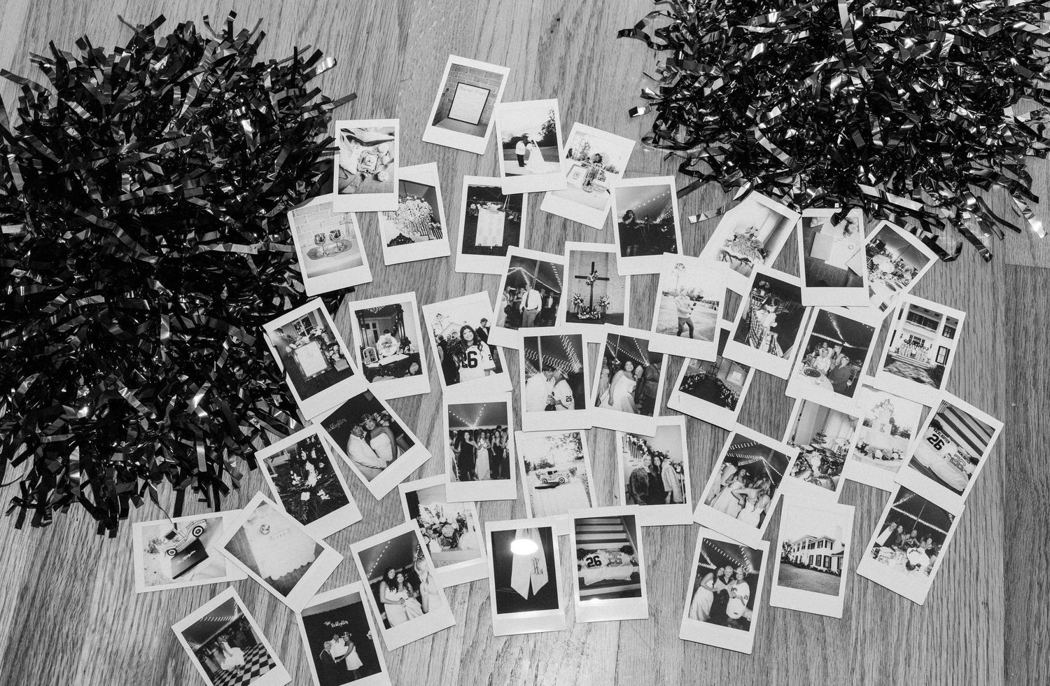 Black and white photo of Instax instant photos spread on floor with green pom pom decorations.