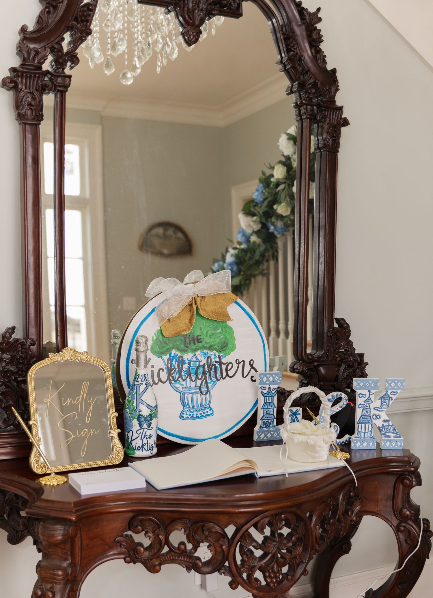 Ornate wooden console table with chinoiserie wedding decor, guest book, and decorative mirror.