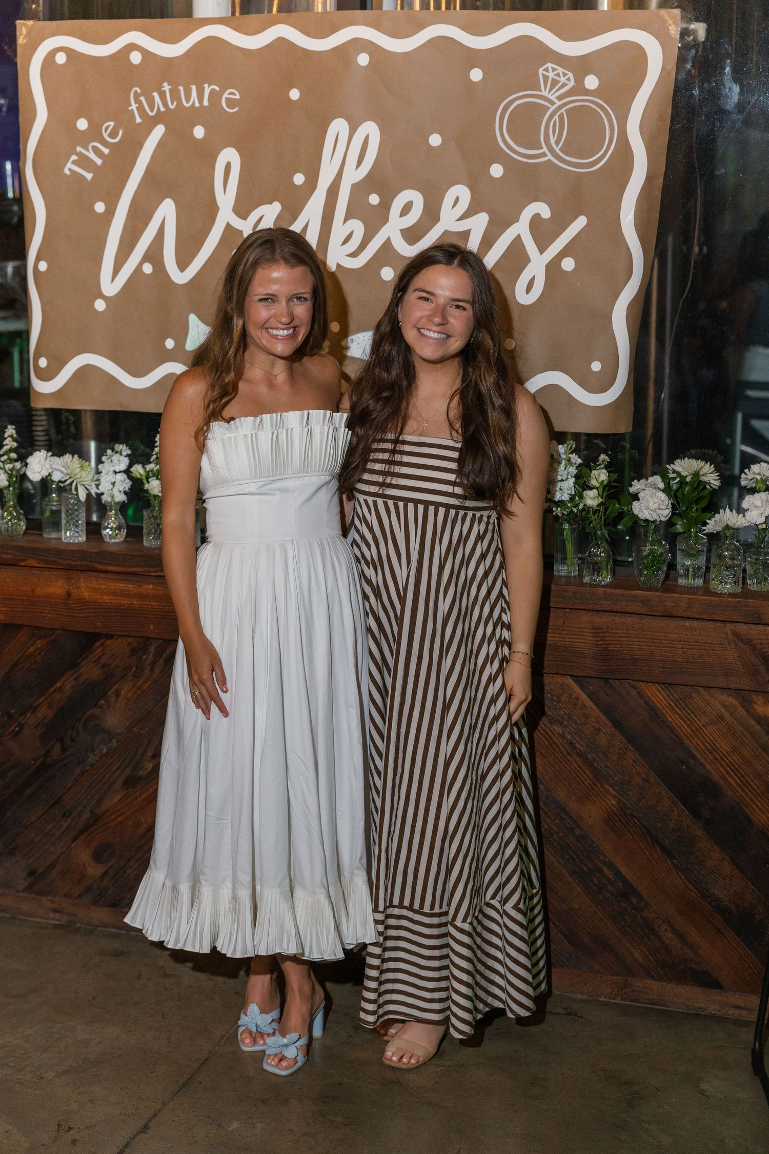 Two women smile together in front of a future Walkers wedding celebration banner.