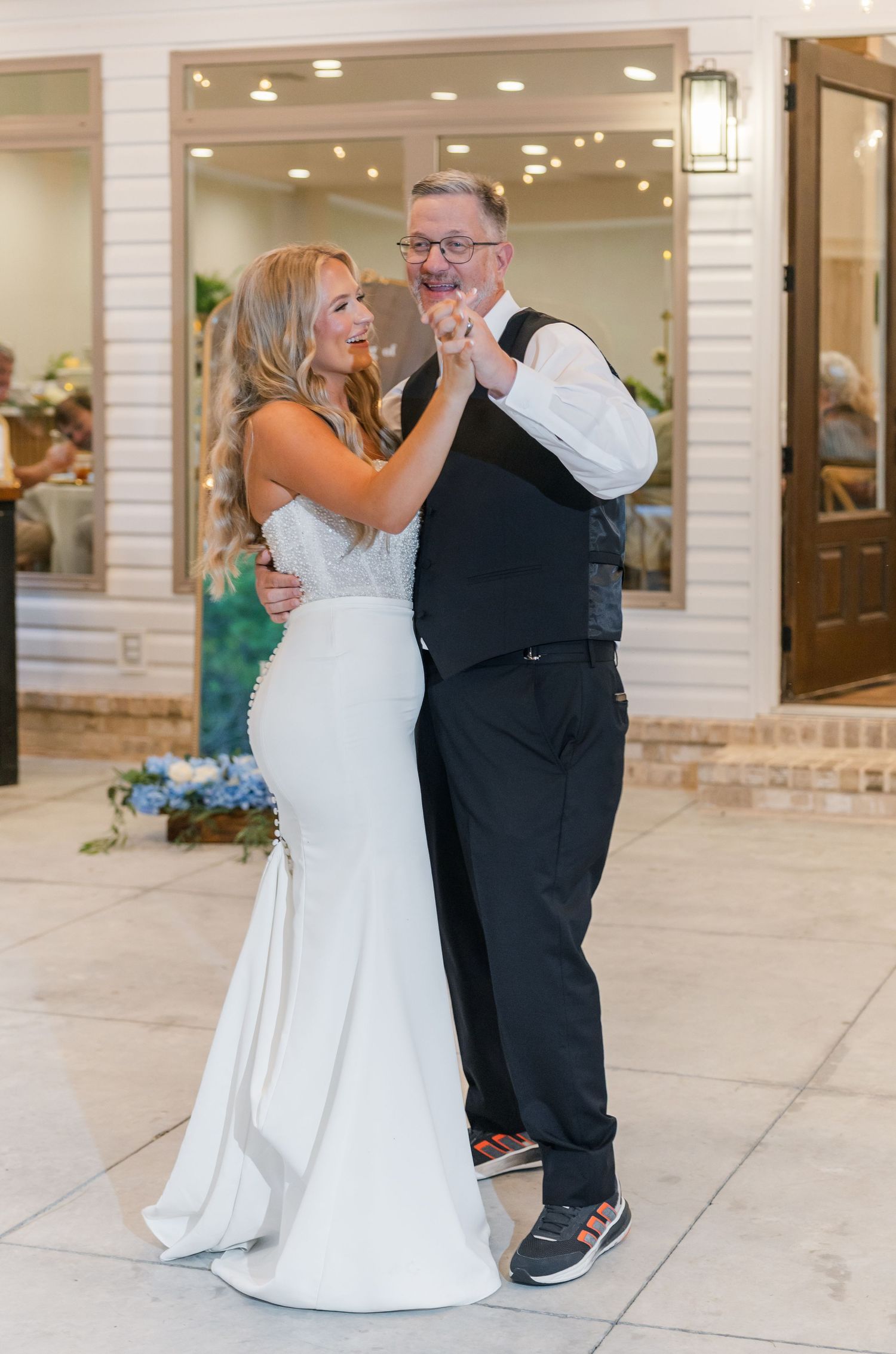 Bride in white mermaid gown shares father-daughter dance at elegant wedding reception.
