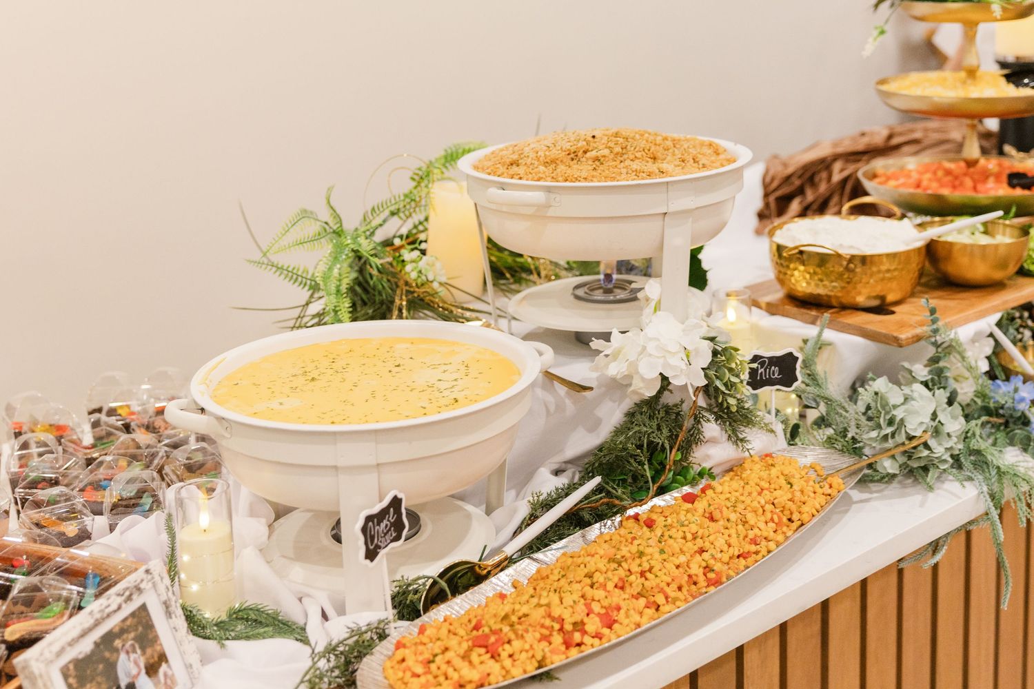 Elegant wedding buffet spread featuring mac and cheese, yellow rice, and colorful dishes with floral accents.