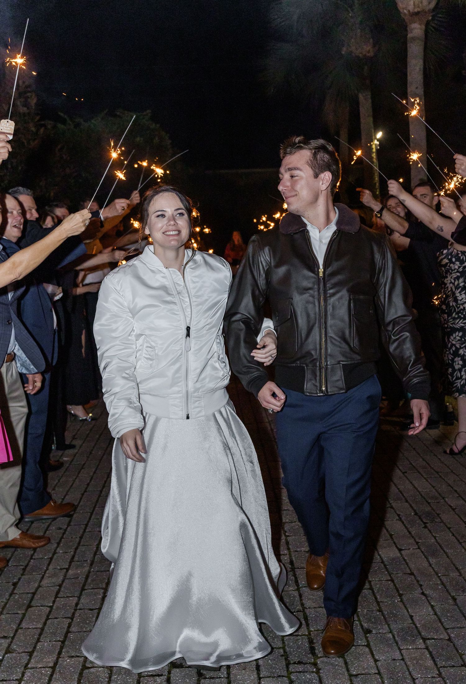 Wedding guests holding sparklers during nighttime celebration on outdoor patio.