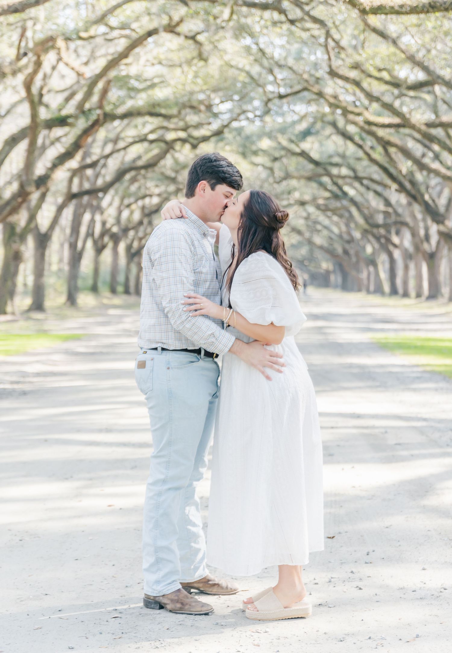 A tender embrace captured between a couple on a beautiful tree-lined avenue.