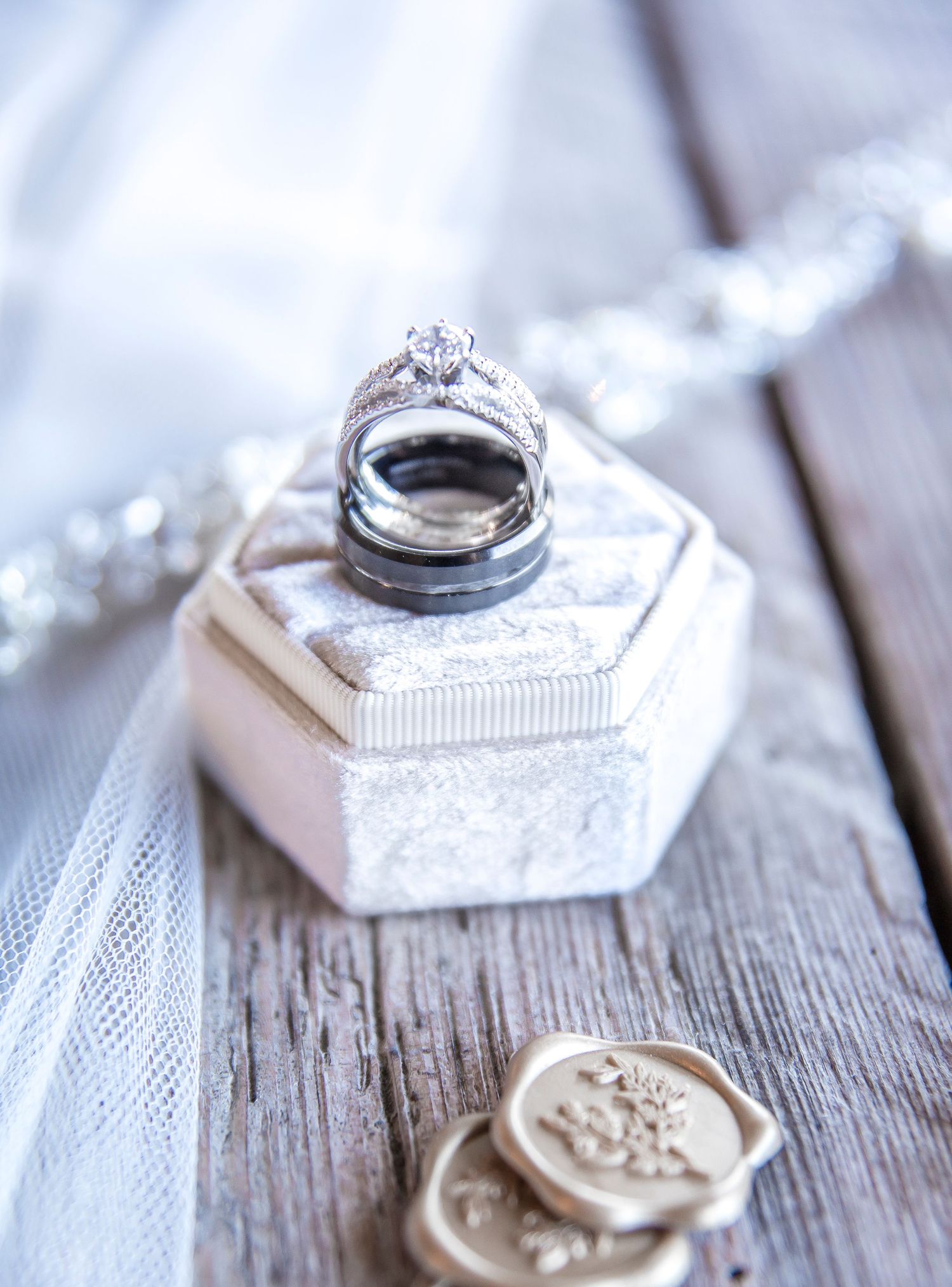 Wedding rings displayed on white hexagonal box with vintage details and wax seals.