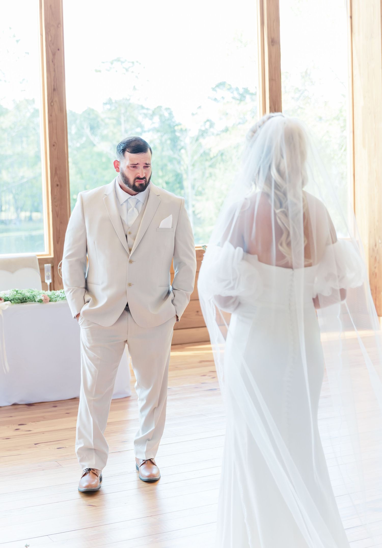 Bride and groom share their first look in a light-filled rustic venue with wooden interior.
