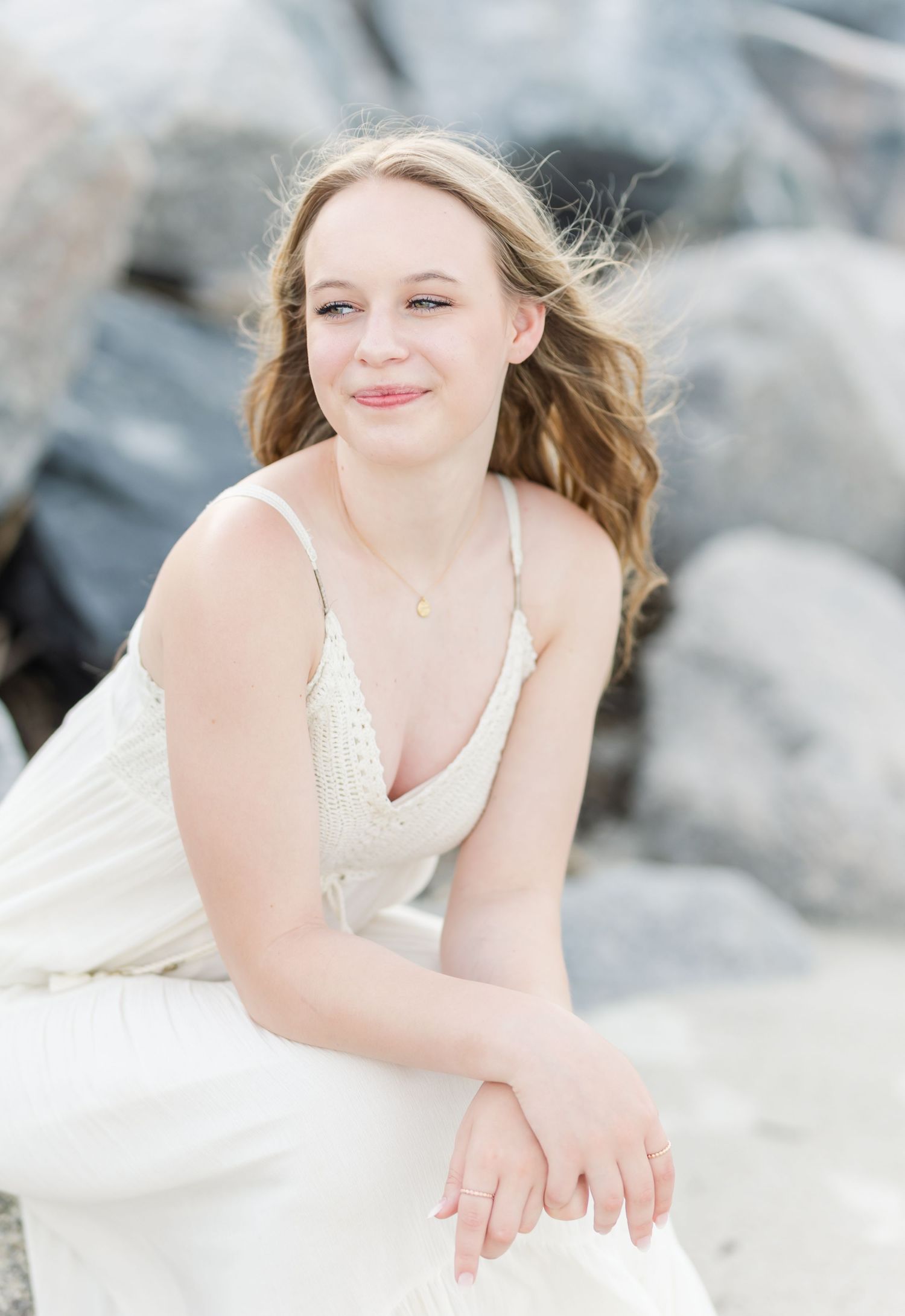 A soft, romantic portrait captured against weathered coastal rocks with gentle natural lighting.