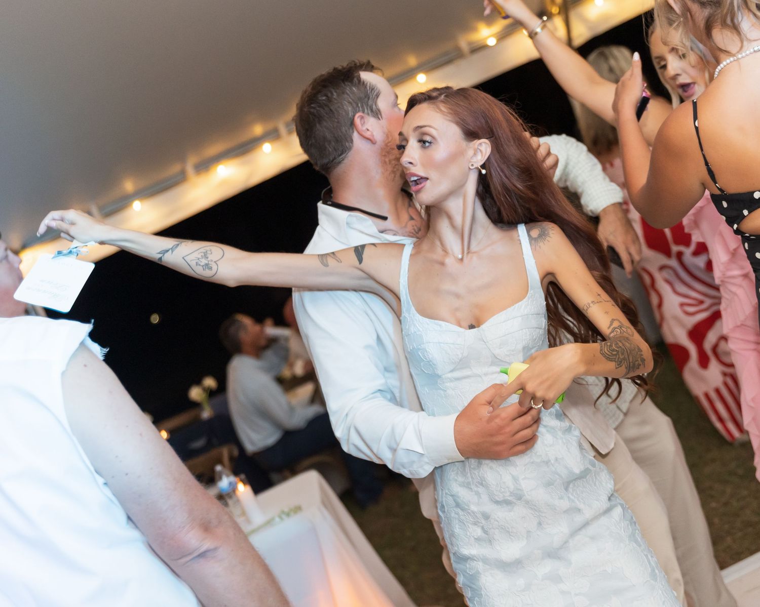 Wedding guests dance and celebrate together on a festively lit dance floor during an evening reception.