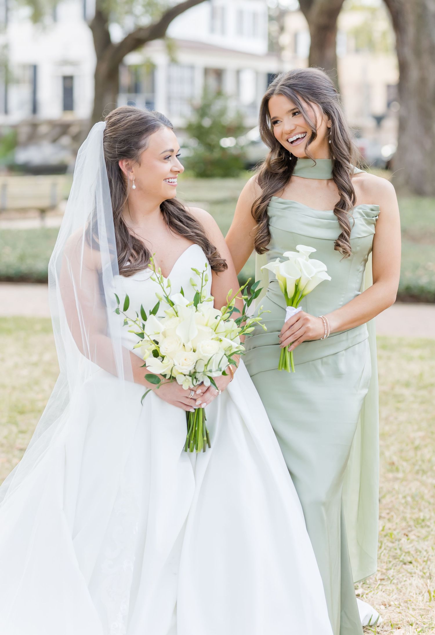 Bridal party laughs together outdoors wearing mint green dresses and white wedding gown.