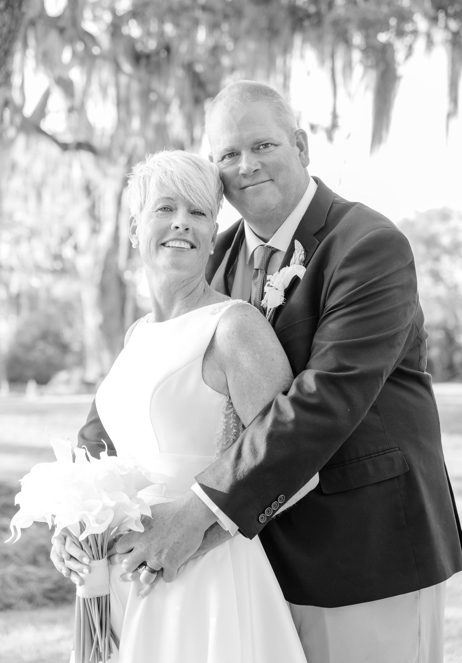 Black and white wedding photo series showing romantic poses of a couple in formal attire outdoors with Spanish moss trees.