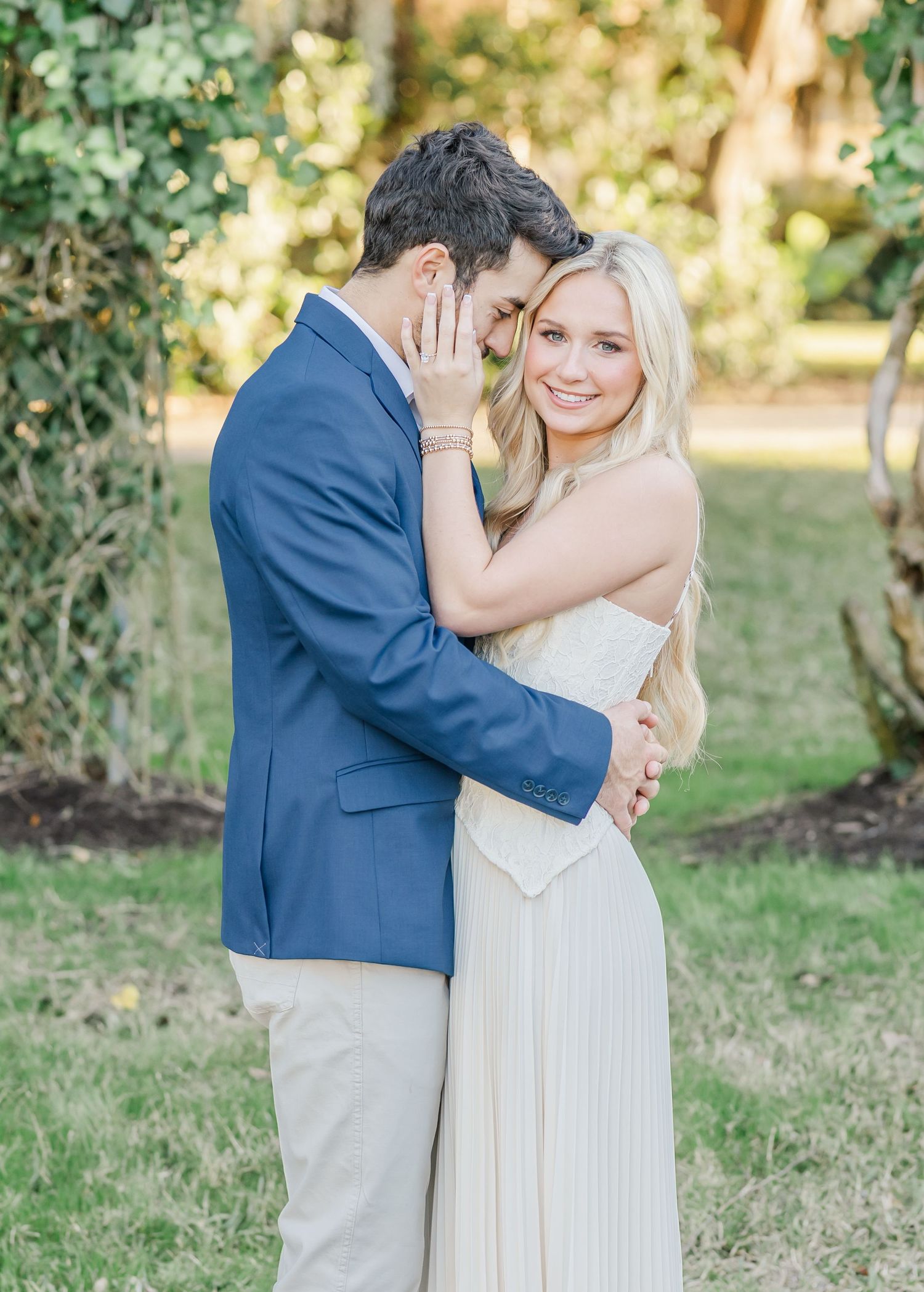 A romantic outdoor wedding photoshoot with a couple embracing in a garden setting, captured in soft natural light.
