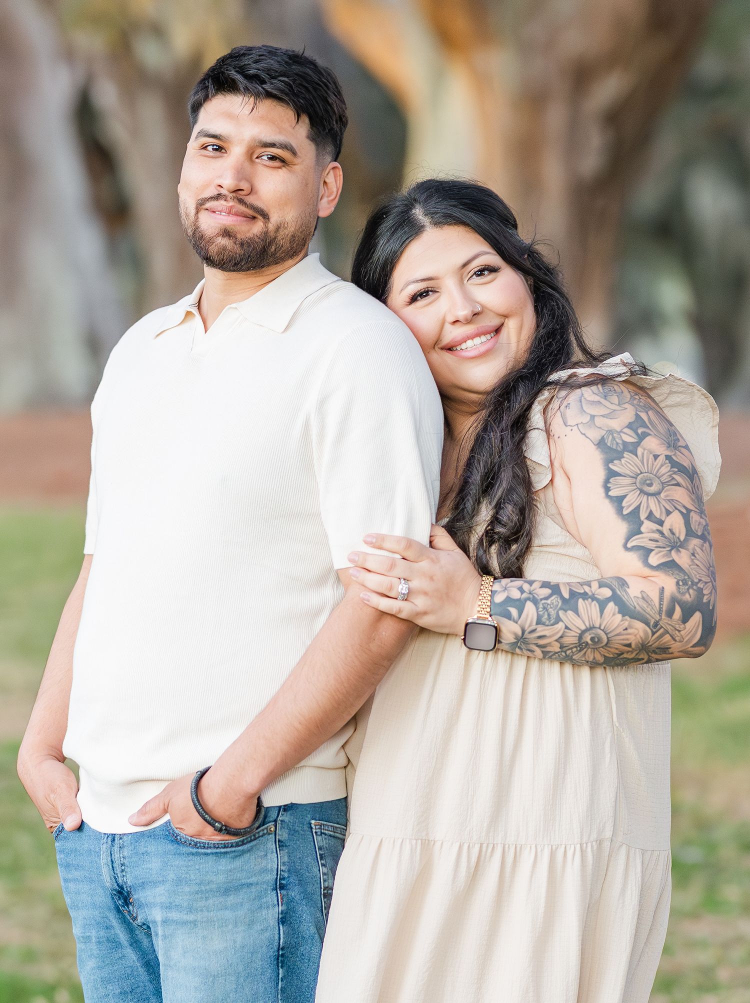 Couple in coordinating white and beige outfits embracing outdoors.