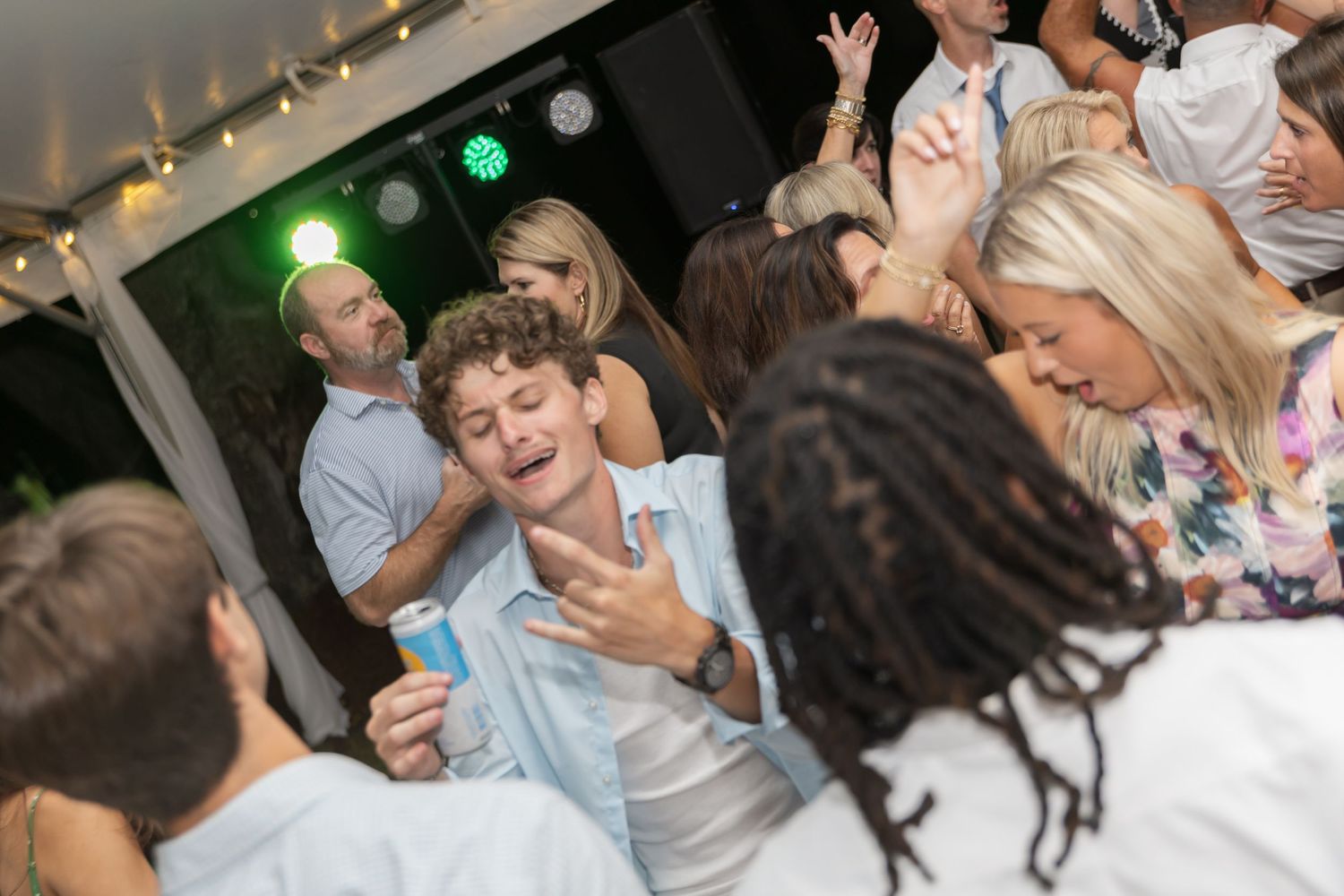 People dancing and celebrating at a lively wedding reception with guests enjoying themselves on the dance floor.