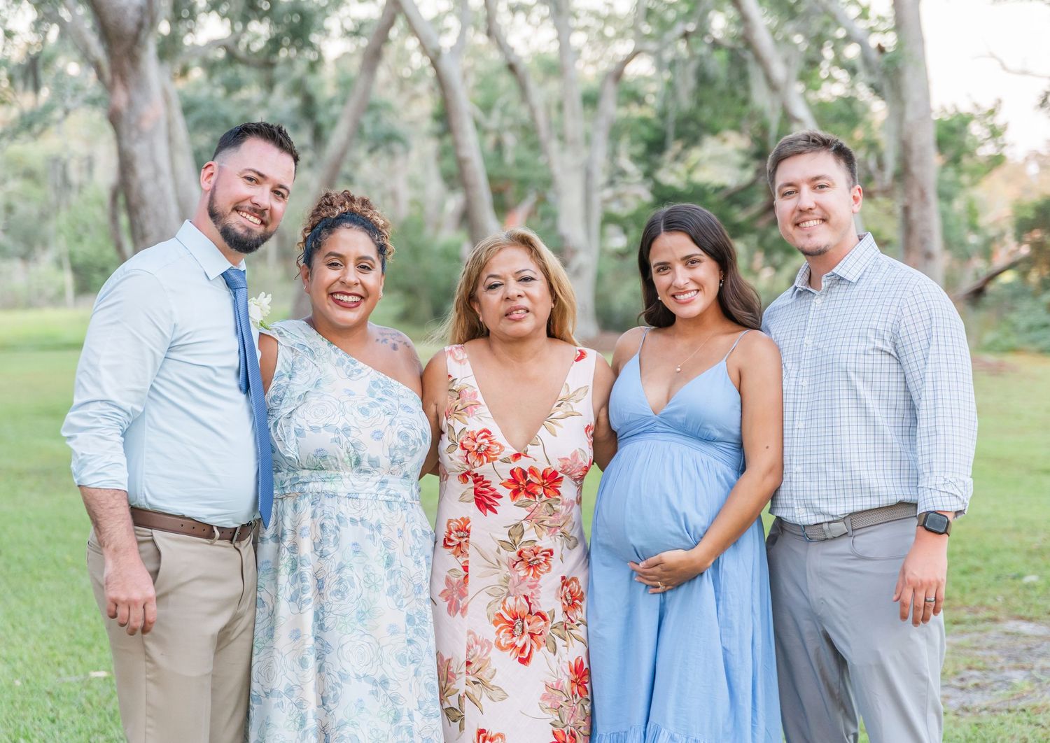 A group in coordinated blue and floral outfits poses together outdoors in a natural garden setting.