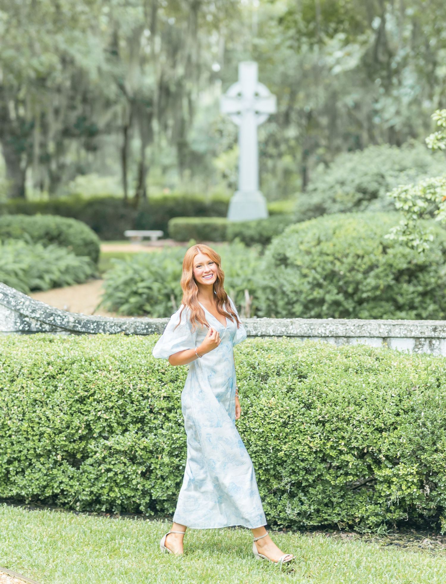 A series of playful poses in a light blue dress against a garden backdrop with manicured hedges.