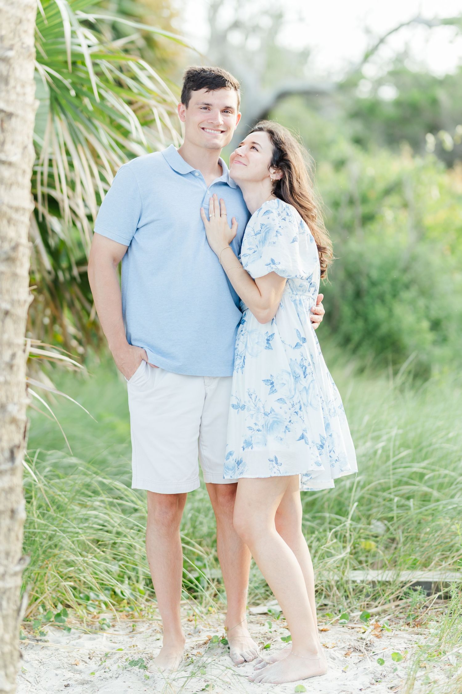 Couple in coordinating blue and white outfits embracing in a tropical palm setting.