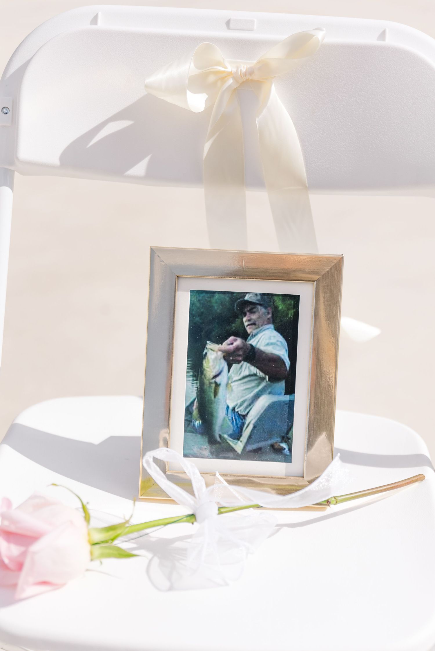 Wedding memorial chair with framed photo and pink rose tribute.