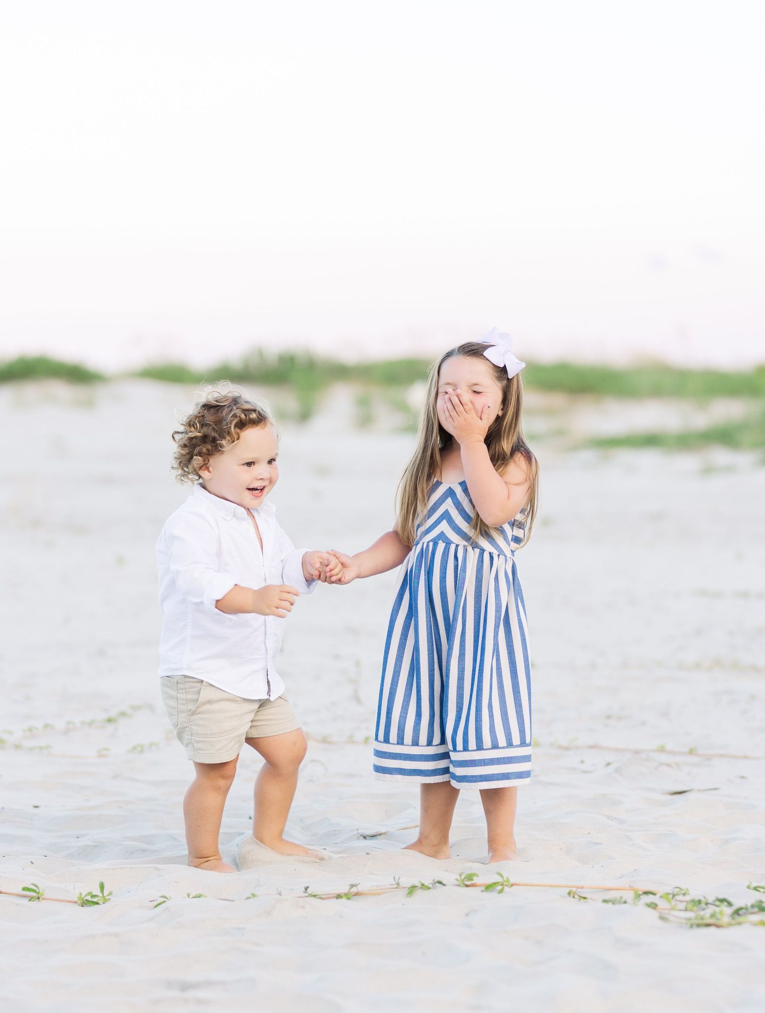 Children playing and interacting together on a bright sandy beach.