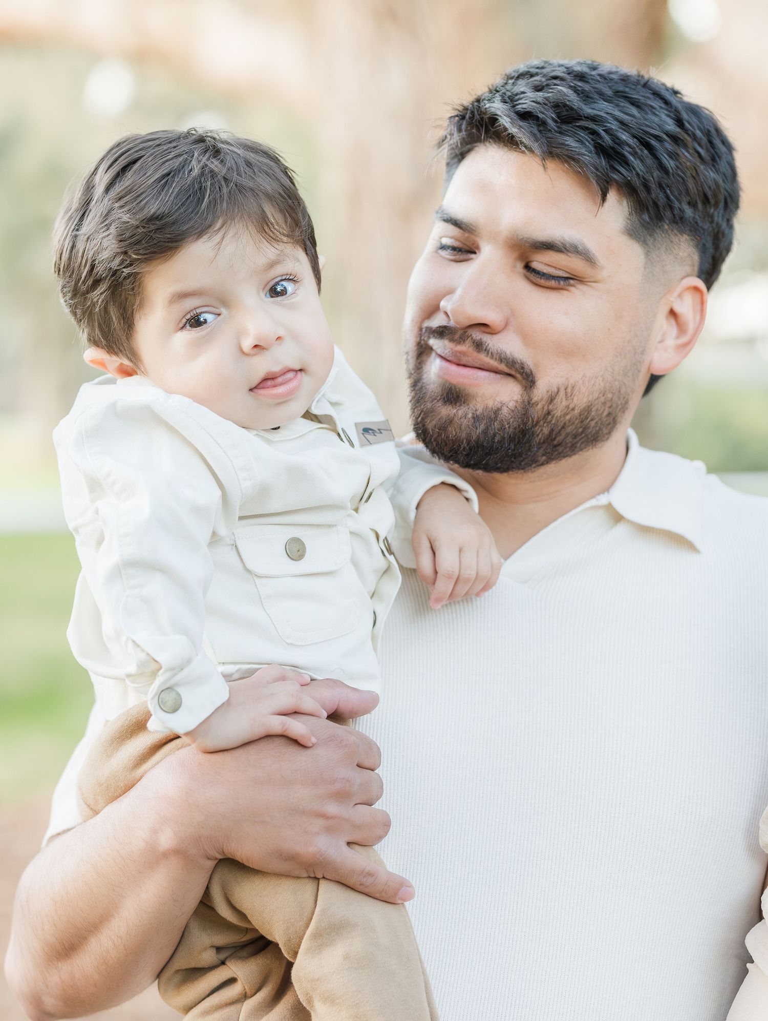 Tender family moment captured in soft natural lighting against a light background.