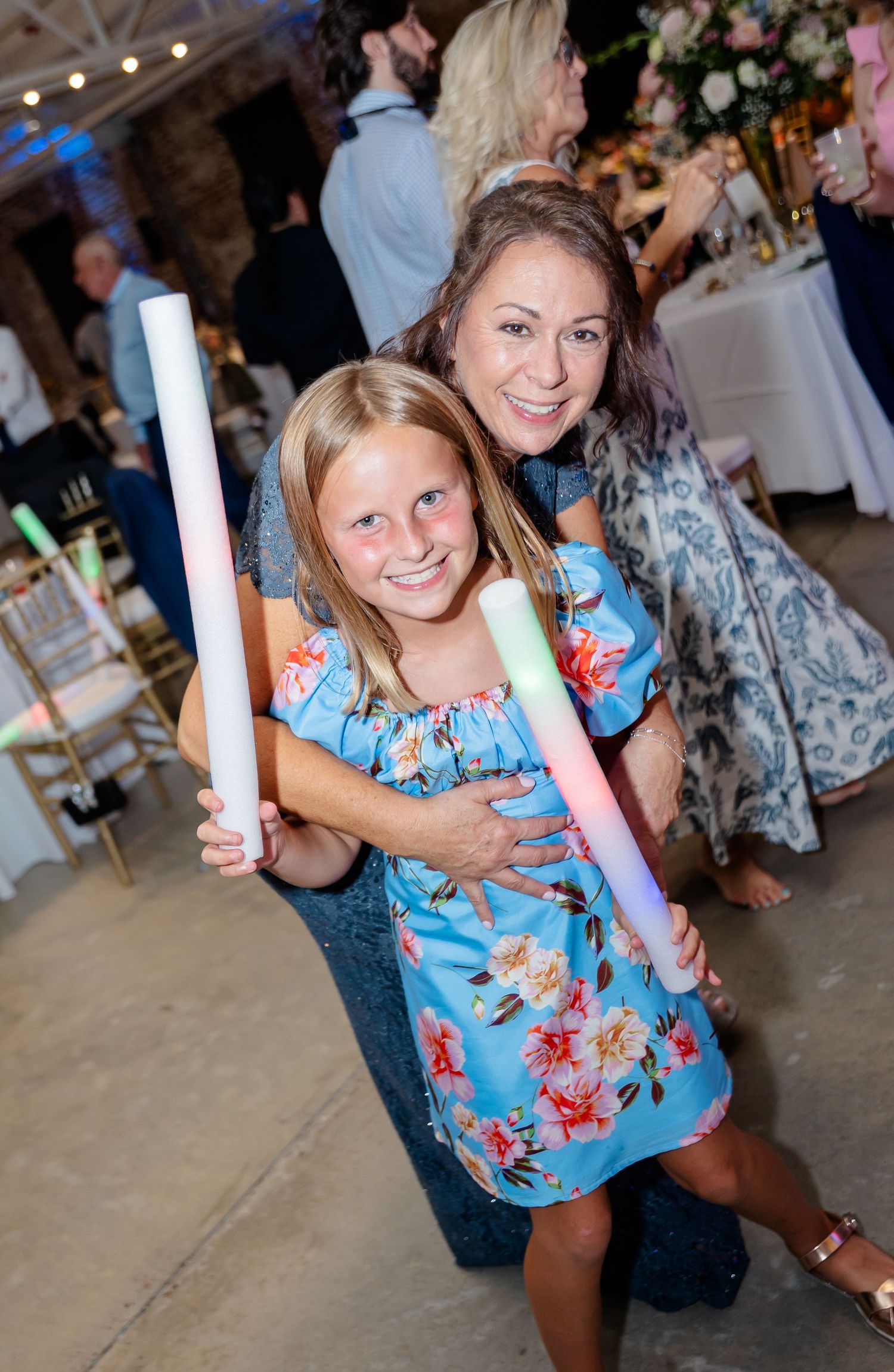 Festive celebration with glow sticks at wedding reception in industrial brick venue.