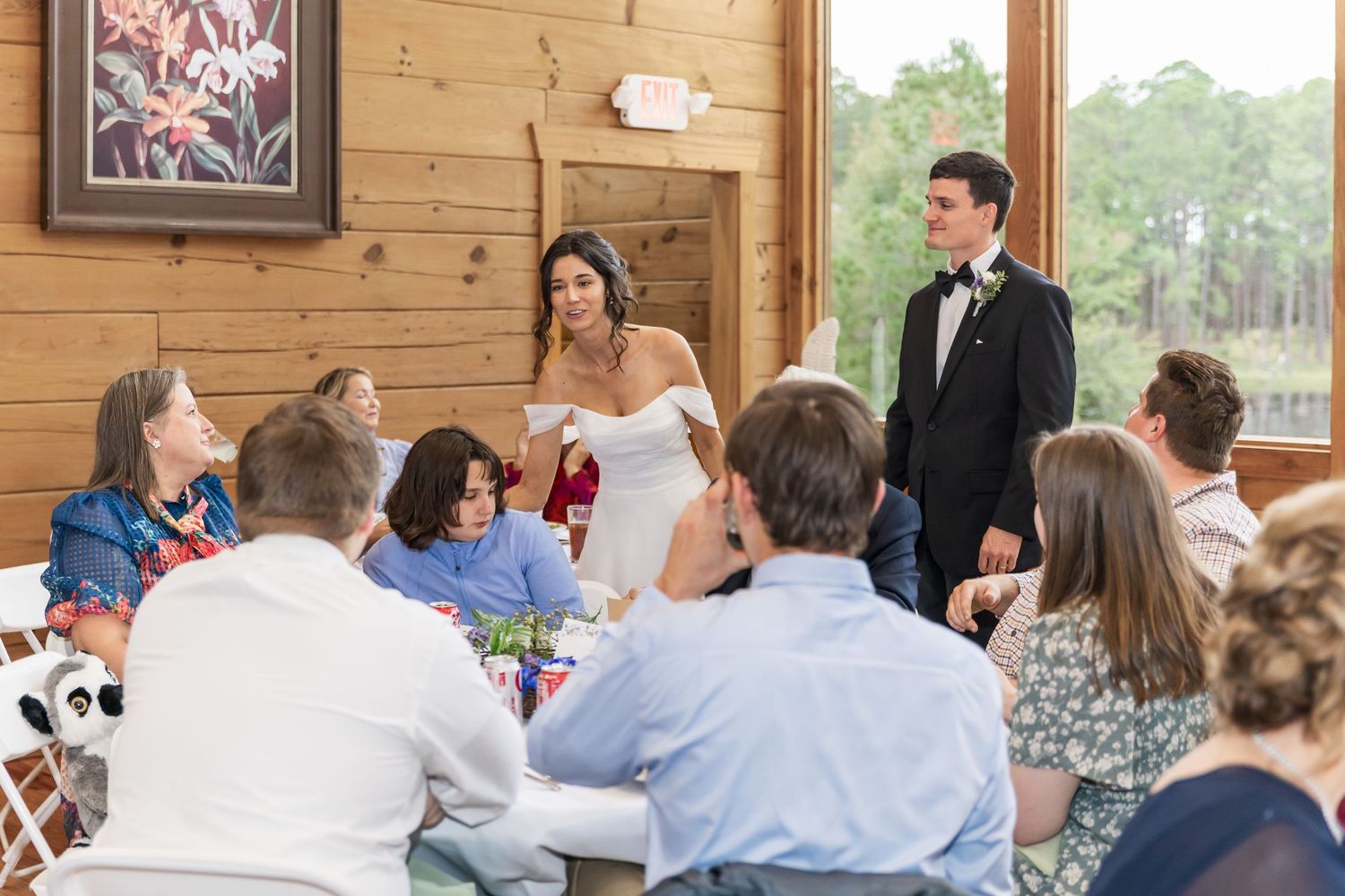 Wedding guests watch the couple's first dance in a sunlit rustic barn venue with wooden walls.