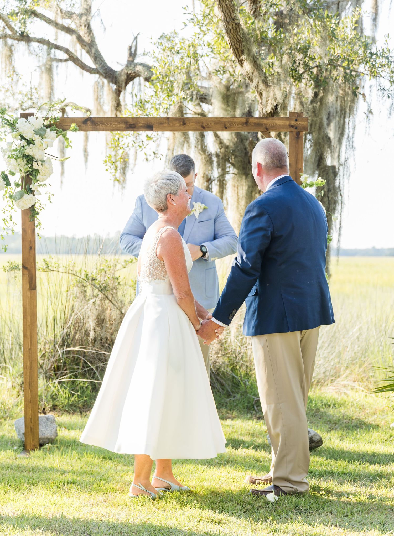An outdoor wedding ceremony sequence under Spanish moss-draped trees with guests seated on white chairs.